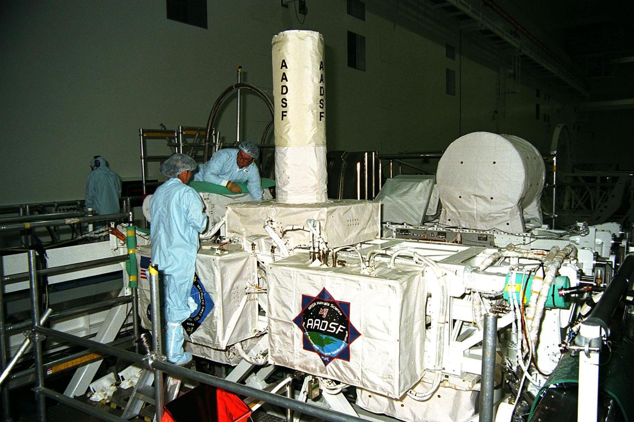 Technicians are monitoring experiments on the United States Microgravity Payload-4 (USMP-4) in preparation for its scheduled launch aboard STS-87 on Nov. 19 from Kennedy Space Center (KSC). USMP-4 experiments are prepared in the Space Station Processing Facility at KSC. The large white vertical cylinder in the center of the photo is the Advanced Automated Directional Solidification Furnace (AADSF), which is a sophisticated materials science facility used for studying a common method of processing semiconductor crystals called directional solidification. The white horizontal tube to the right is the Isothermal Dendritic Growth Experiment (IDGE), which will be used to study the dendritic solidification of molten materials in the microgravity environment