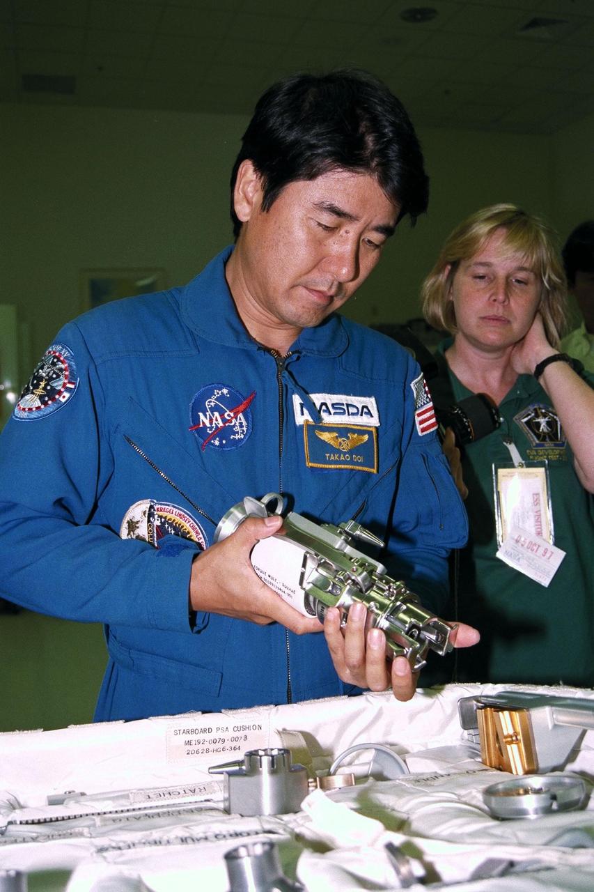 STS-87 Mission Specialist Takao Doi , Ph.D., of the National Space Development Agency of Japan, participates in the Crew Equipment Integration Test (CEIT) in Kennedy Space Center’s (KSC's) Vertical Processing Facility. Glenda Laws, the extravehicular activity (EVA) coordinator, Johnson Space Center, stands behind Dr. Doi. The CEIT gives astronauts an opportunity to get a hands-on look at the payloads with which they will be working on-orbit. STS-87 will be the fourth United States Microgravity Payload and flight of the Spartan-201 deployable satellite. During the mission, Dr. Doi will be the first Japanese astronaut to perform a spacewalk. STS-87 is scheduled for a Nov. 19 liftoff from KSC