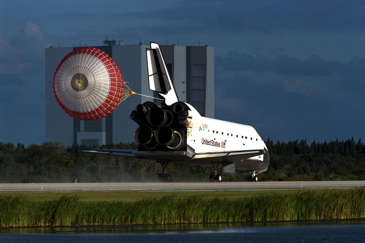 KENNEDY SPACE CENTER, Fla. -- The orbiter drag chute deploys after the Space Shuttle orbiter Atlantis lands on Runway 15 of the KSC Shuttle Landing Facility (SLF) at the conclusion of the nearly 11-day STS-86 mission. The Vehicle Assembly Building (VAB) can be seen in the background. Main gear touchdown was at 5:55:09 p.m. EDT, Oct. 6, 1997, with an unofficial mission-elapsed time of 10 days, 19 hours, 20 minutes and 50 seconds. The first two KSC landing opportunities on Sunday were waved off because of weather concerns. The 87th Space Shuttle mission was the 40th landing of the Shuttle at KSC. On Sunday evening, the Space Shuttle program reached a milestone: The total flight time of the Shuttle passed the two-year mark. STS86 was the seventh of nine planned dockings of the Space Shuttle with the Russian Space Station Mir. STS-86 Mission Specialist David A. Wolf replaced NASA astronaut and Mir 24 crew member C. Michael Foale, who has been on the Mir since mid-May. Foale returned to Earth on Atlantis with the remainder of the STS-86 crew. The other crew members are Commander James D. Wetherbee, Pilot Michael J. Bloomfield, and Mission Specialists Wendy B. Lawrence, Scott E. Parazynski, Vladimir Georgievich Titov of the Russian Space Agency, and Jean-Loup J.M. Chretien of the French Space Agency, CNES. Wolf is scheduled to remain on the Mir until the STS-89 Shuttle mission in January. Besides the docking and crew exchange, STS-86 included the transfer of more than three-and-a-half tons of science/logistical equipment and supplies between the two orbiting spacecraft. Parazynski and Titov also conducted a spacewalk while Atlantis and the Mir were docked