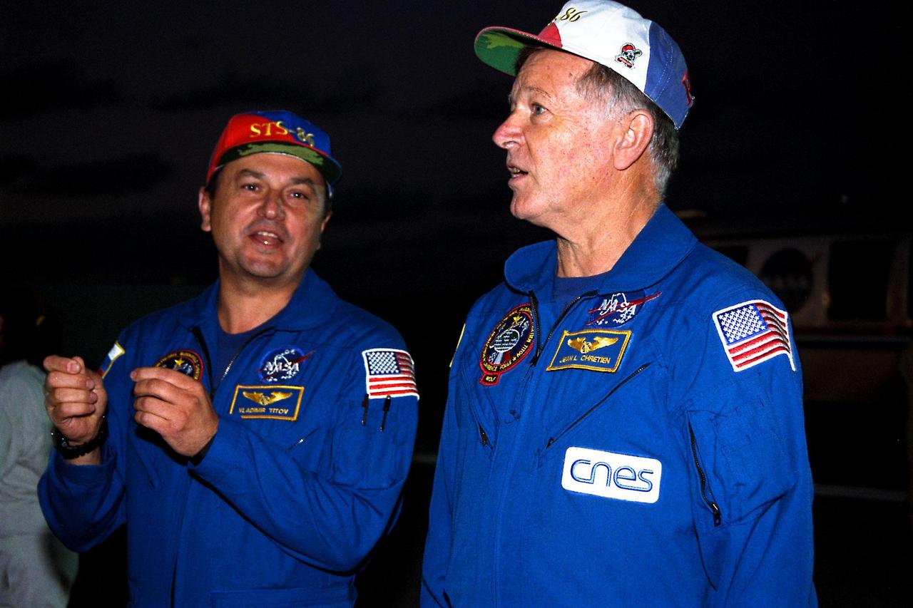 STS-86 Mission Specialists Vladimir Georgievich Titov of the Russian Space Agency, at left, and Jean-Loup J.M. Chretien of the French Space Agency, CNES, talk about their recently completed U.S. space mission while walking under and around the orbiter Atlantis after landing on KSC’s Runway 15 of the Shuttle Landing Facility. This was Chretien’s third spaceflight, but first on the Space Shuttle. Titov previously flew four times in space, including once on the Space Shuttle as a mission specialist on STS-63. The nearly 11-day STS-86 mission ended with main gear touchdown at 5:55:09 p.m. EDT, Oct. 6, 1997. STS-86 was the seventh docking of the Space Shuttle with the Russian Space Station Mir