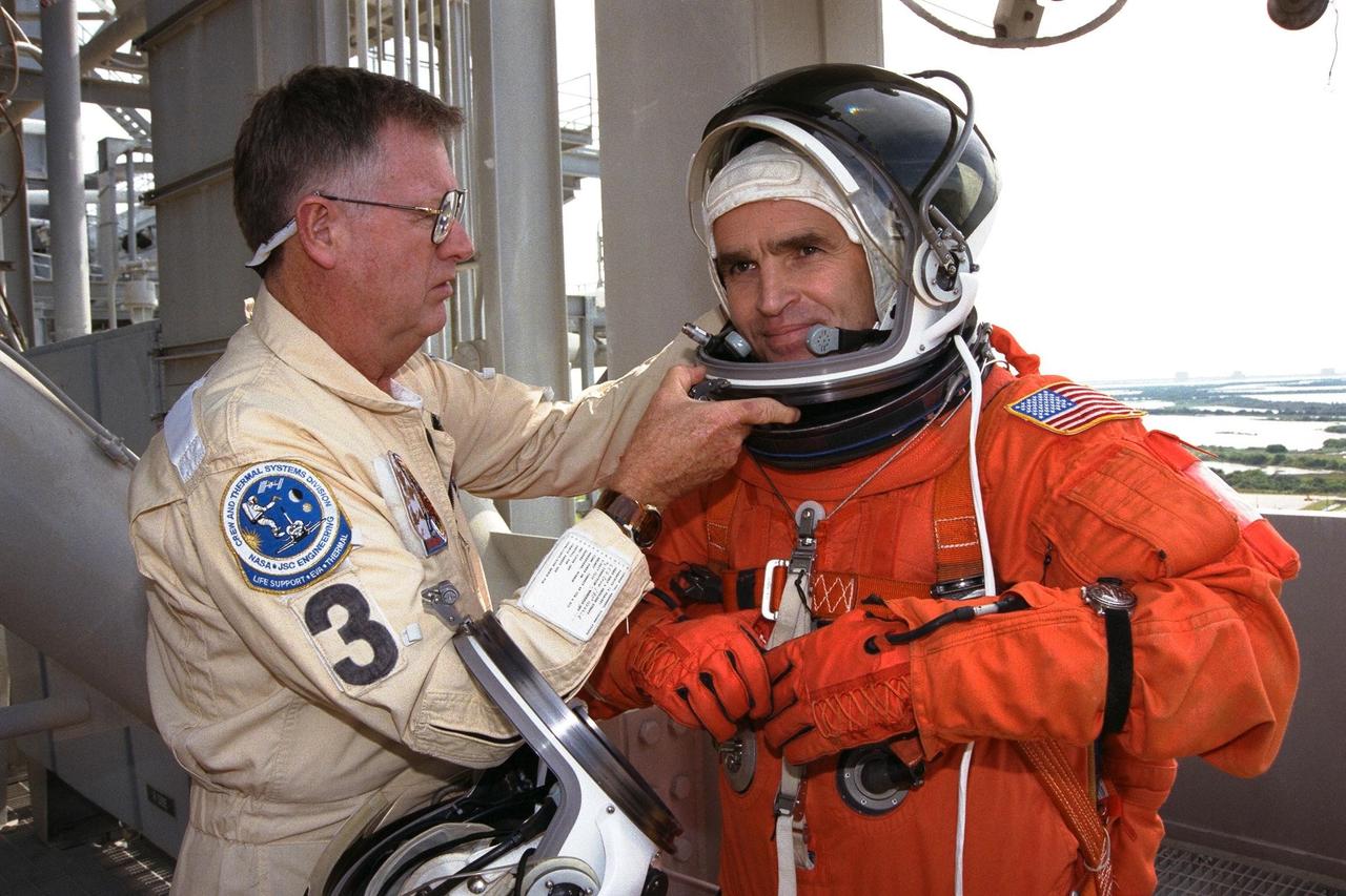 STS-87 Payload Specialist Leonid Kadenyuk, at right, of the National Space Agency of Ukraine (NSAU) is assisted into his orange launch and entry spacesuit ensemble by NASA Suit Technician Al Rochford, at left, before participating in Terminal Countdown Demonstration Test (TCDT) activities. The crew of the STS-87 mission is scheduled for launch Nov. 19 aboard the Space Shuttle Columbia. The TCDT is held at KSC prior to each Space Shuttle flight providing the crew of each mission opportunities to participate in simulated countdown activities. The TCDT ends with a mock launch countdown culminating in a simulated main engine cut-off. The crew also spends time undergoing emergency egress training exercises at the pad and has an opportunity to view and inspect the payloads in the orbiter's payload bay
