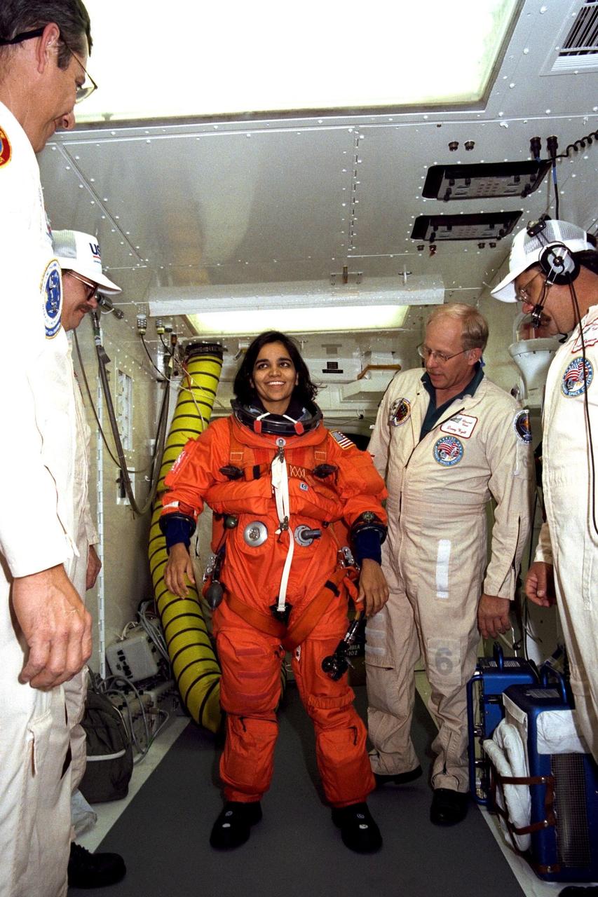 STS-87 Mission Specialist Kalpana Chawla, Ph.D., is assisted with her orange launch and entry spacesuit by NASA suit technicians at Launch Pad 39B during Terminal Countdown Demonstration Test (TCDT) activities. The crew of the STS-87 mission is scheduled for launch Nov. 19 aboard the Space Shuttle Columbia. The TCDT is held at KSC prior to each Space Shuttle flight providing the crew of each mission opportunities to participate in simulated countdown activities. The TCDT ends with a mock launch countdown culminating in a simulated main engine cut-off. The crew also spends time undergoing emergency egress training exercises at the pad and has an opportunity to view and inspect the payloads in the orbiter's payload bay