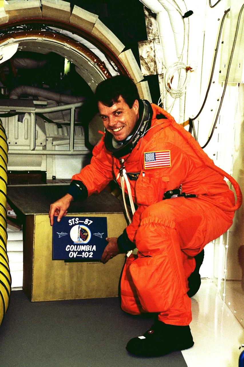 STS-87 Commander Kevin Kregel holds the crew patch in front of Columbia’s entry hatch at Launch Pad 39B during Terminal Countdown Demonstration Test (TCDT) activities. The crew of the STS-87 mission is scheduled for launch Nov. 19 aboard the Space Shuttle Columbia. The TCDT is held at KSC prior to each Space Shuttle flight providing the crew of each mission opportunities to participate in simulated countdown activities. The TCDT ends with a mock launch countdown culminating in a simulated main engine cut-off. The crew also spends time undergoing emergency egress training exercises at the pad and has an opportunity to view and inspect the payloads in the orbiter's payload bay
