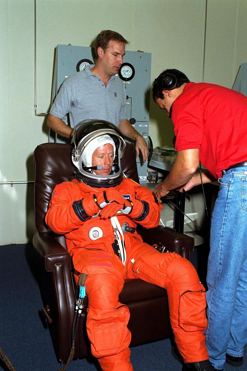 STS-87 Pilot Steven Lindsey dons his launch and entry suit with the help of two assistants in the Operations and Checkout Building. Shortly, he and the five other crew members of STS-87 will depart for Launch Pad 39B, where the Space Shuttle Columbia awaits liftoff on a 16-day mission to perform microgravity and solar research. Although this is his first Shuttle flight, Lindsey has logged more than 2,700 hours of flying time in 49 different types of aircraft