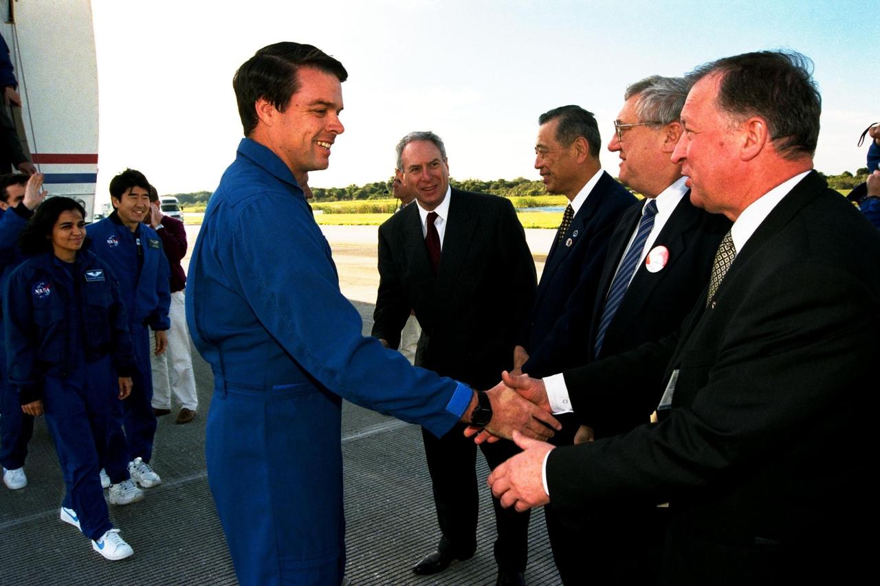 STS-87 Commander Kevin Kregel, center, shakes hands with the deputy director general of the National Space Agency of Ukraine (NSAU), Eduard Kuznetsov, at far right. Next to Kuznetsov is the Honorable Yuri Shcherbak, Ukraine's ambassador to the United States, standing with the president of the National Space Development Agency (NASDA) of Japan, Isao Uchida, and NASA Administrator Daniel Goldin (center). Approaching the VIPs from the left of the photo are Mission Specialists Kalpana Chawla, Ph.D., and Takao Doi, Ph.D., of NASDA. STS-87 concluded its mission with a main gear touchdown at 7:20:04 a.m. EST Dec. 5, at KSC's Shuttle Landing Facility Runway 33, drawing the 15-day, 16-hour and 34-minute-long mission of 6.5 million miles to a close. Also onboard the orbiter were Pilot Steven Lindsey; Mission Specialist Winston Scott; and Payload Specialist Leonid Kadenyuk of NSAU. During the 88th Space Shuttle mission, the crew performed experiments on the United States Microgravity Payload-4 and pollinated plants as part of the Collaborative Ukrainian Experiment. This was the 12th landing for Columbia at KSC and the 41st KSC landing in the history of the Space Shuttle program