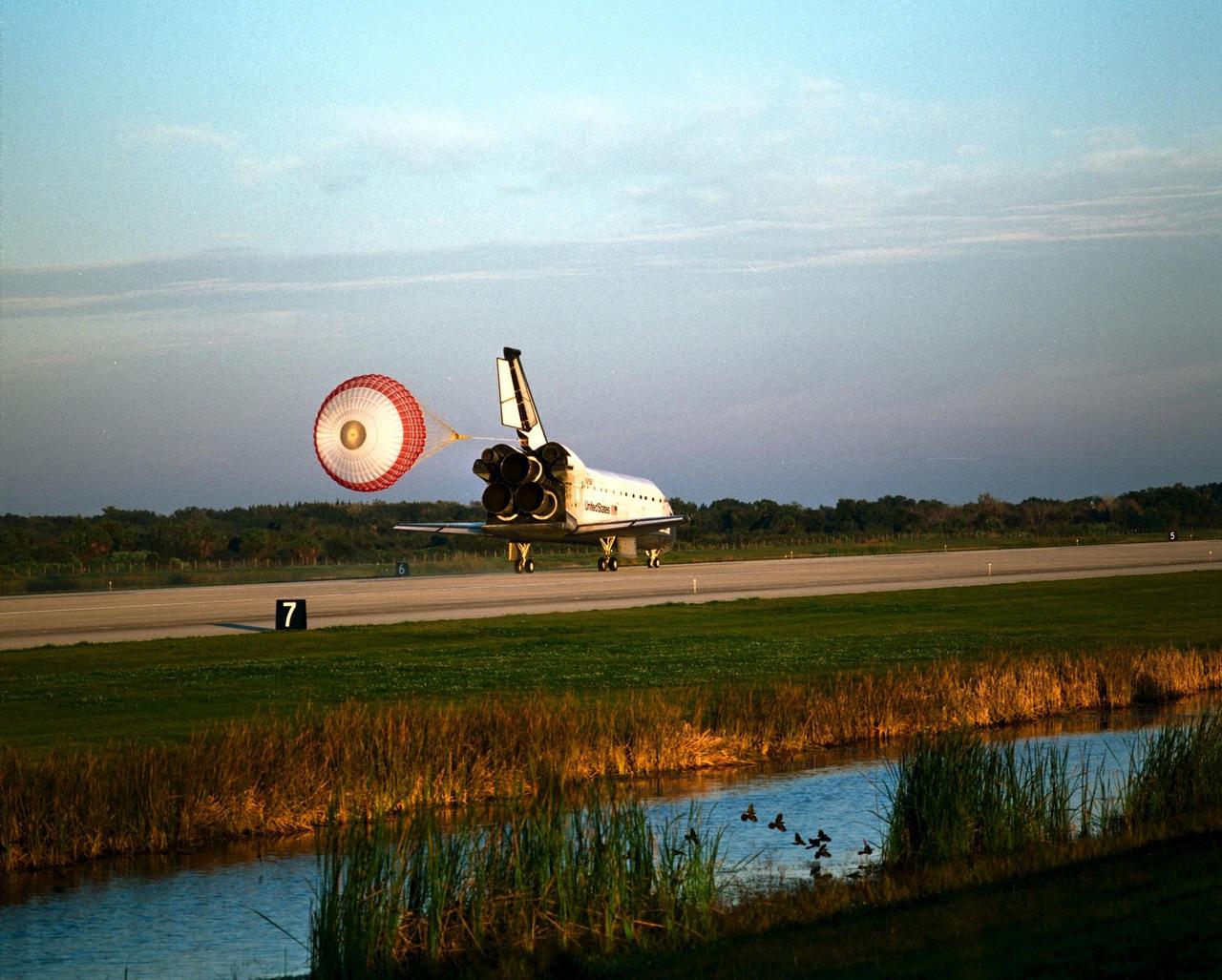 With Commander Kevin Kregel and Pilot Steven Lindsey at the controls, the orbiter Columbia, with its drag chute deployed, touches down on Runway 33 at KSC’s Shuttle Landing Facility at 7:20:04 a.m. EST Dec. 5 to complete the 15-day, 16-hour and 34-minute-long STS-87 mission of 6.5 million miles. Also onboard the orbiter are Mission Specialists Winston Scott; Kalpana Chawla, Ph.D.; and Takao Doi, Ph.D., of the National Space Development Agency of Japan; along with Payload Specialist Leonid Kadenyuk of the National Space Agency of Ukraine. During the 88th Space Shuttle mission, the crew performed experiments on the United States Microgravity Payload-4 and pollinated plants as part of the Collaborative Ukrainian Experiment. This was the 12th landing for Columbia at KSC and the 41st KSC landing in the history of the Space Shuttle program