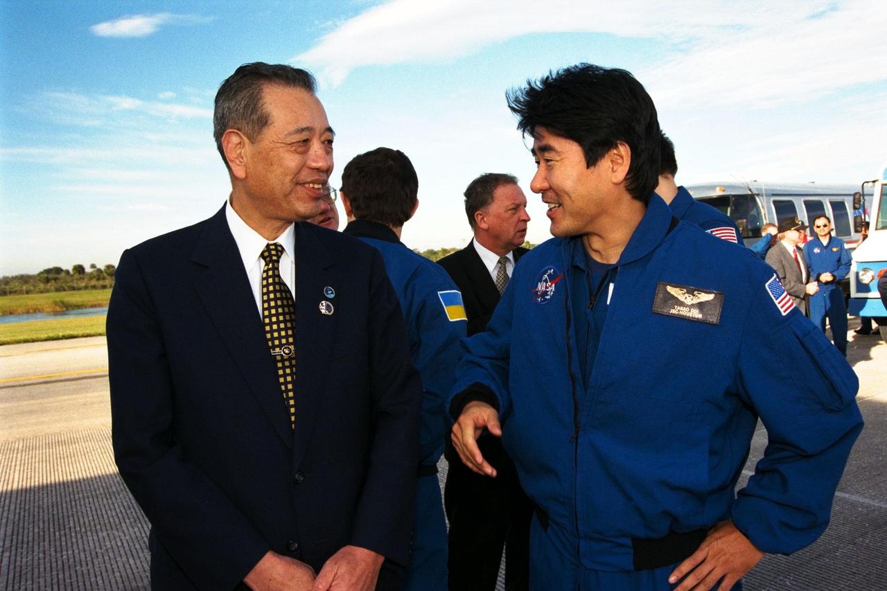The president of the National Space Development Agency (NASDA) of Japan, Isao Uchida, at left, chats with STS-87 Mission Specialist Takao Doi, Ph.D., of NASDA, shortly after the landing of Columbia at Kennedy Space Center. STS-87 concluded its mission with a main gear touchdown at 7:20:04 a.m. EST Dec. 5, at KSC's Shuttle Landing Facility Runway 33, drawing the 15-day, 16-hour and 34-minute-long mission of 6.5 million miles to a close. Also onboard the orbiter were Commander Kevin Kregel; Pilot Steven Lindsey; Mission Specialists Winston Scott and Kalpana Chawla, Ph.D.; and Payload Specialist Leonid Kadenyuk of the National Space Agency of Ukraine. During the 88th Space Shuttle mission, the crew performed experiments on the United States Microgravity Payload-4 and pollinated plants as part of the Collaborative Ukrainian Experiment. This was the 12th landing for Columbia at KSC and the 41st KSC landing in the history of the Space Shuttle program