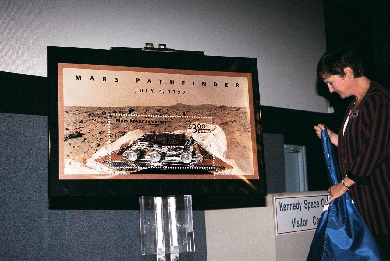 Nancy Warren, supervisor of stamp distribution for the U.S. Post Office, unveils the $3 commemorative Mars Pathfinder postage stamp at Kennedy Space Center's Visitor Complex on the second day of its issue. The stamp was first issued on Dec. 10 at the Jet Propulsion Laboratory, Pasadena, Calif. It depicts the Sojourner rover at rest on the Pathfinder spacecraft with a panoramic Martian view that is based on one of the first mission images sent back to Earth