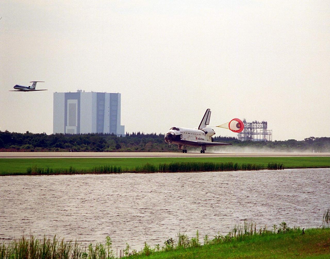 Framed by the Vehicle Assembly Building in the distance, at left, and the Mate-Demate Device, the Space Shuttle Atlantis with its drag chute deployed touches down on KSC’s Runway 33 at the conclusion of the STS-84 mission. The Shuttle Training Aircraft with astronaut Kenneth D. Cockrell at the controls is flying in front of Atlantis. Cockrell is acting deputy chief of the Astronaut Office. Main gear touchdown was at 9:27:44 EDT on May 24, 1997. The first landing opportunity was waved off because of low cloud cover. It was the 37th landing at KSC since the Shuttle program began in 1981, and the eighth consecutive landing at KSC. STS-84 was the sixth of nine planned dockings of the Space Shuttle with the Russian Space Station Mir. Atlantis was docked with the Mir for five days. STS-84 Mission Specialist C. Michael Foale replaced astronaut and Mir 23 crew member Jerry M. Linenger, who has been on the Russian space station since Jan. 15. Linenger returned to Earth on Atlantis with the rest of the STS-84 crew, Mission Commander Charles J. Precourt, Pilot Eileen Marie Collins, and Mission Specialists Carlos I. Noriega, Edward Tsang Lu, Elena V. Kondakova of the Russian Space Agency and Jean-Francois Clervoy of the European Space Agency. Foale is scheduled to remain on the Mir for approximately four months, until he is replaced by STS-86 crew member Wendy B. Lawrence in September. Besides the docking and crew exchange, STS-84 included the transfer of more than 7,300 pounds of water, logistics and science experiments and hardware to and from the Mir. Scientific experiments conducted during the STS-84 mission, and scheduled for Foale’s stay on the Mir, are in the fields of advanced technology, Earth sciences, fundamental biology, human life sciences, International Space Station risk mitigation, microgravity sciences and space sciences