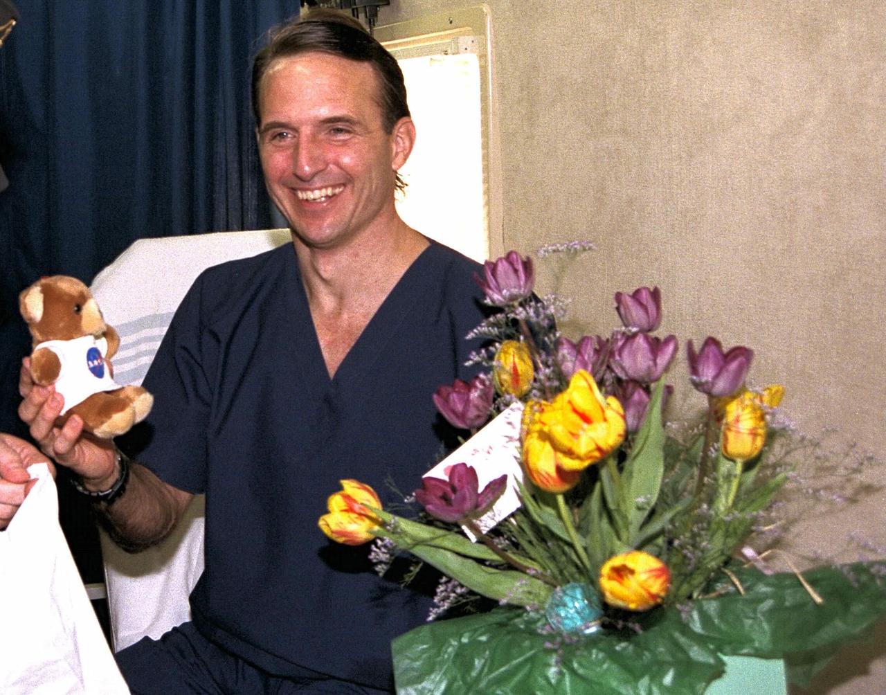 Astronaut and recent Mir 23 crew member Jerry M. Linenger holds a stuffed bear he was given by NASA Administrator Daniel Goldin at the conclusion of the STS-84 Space Shuttle mission. STS-84 was the sixth docking of the Shuttle with the Russian Space Station Mir, where Linenger has lived and worked the past four months. Goldin presented several gifts to Linenger in the Crew Transport Vehicle shortly after landing of the Space Shuttle orbiter Atlantis on KSC’s Runway 33. Besides the bear for Linenger’s 18-month-old son, John, Goldin gave the astronaut flowers for Linenger’s wife, Kathryn; and a rattle for the Linengers’ unborn child who is due next month. Linenger was replaced on the Russian space station by STS-84 Mission Specialist C. Michael Foale