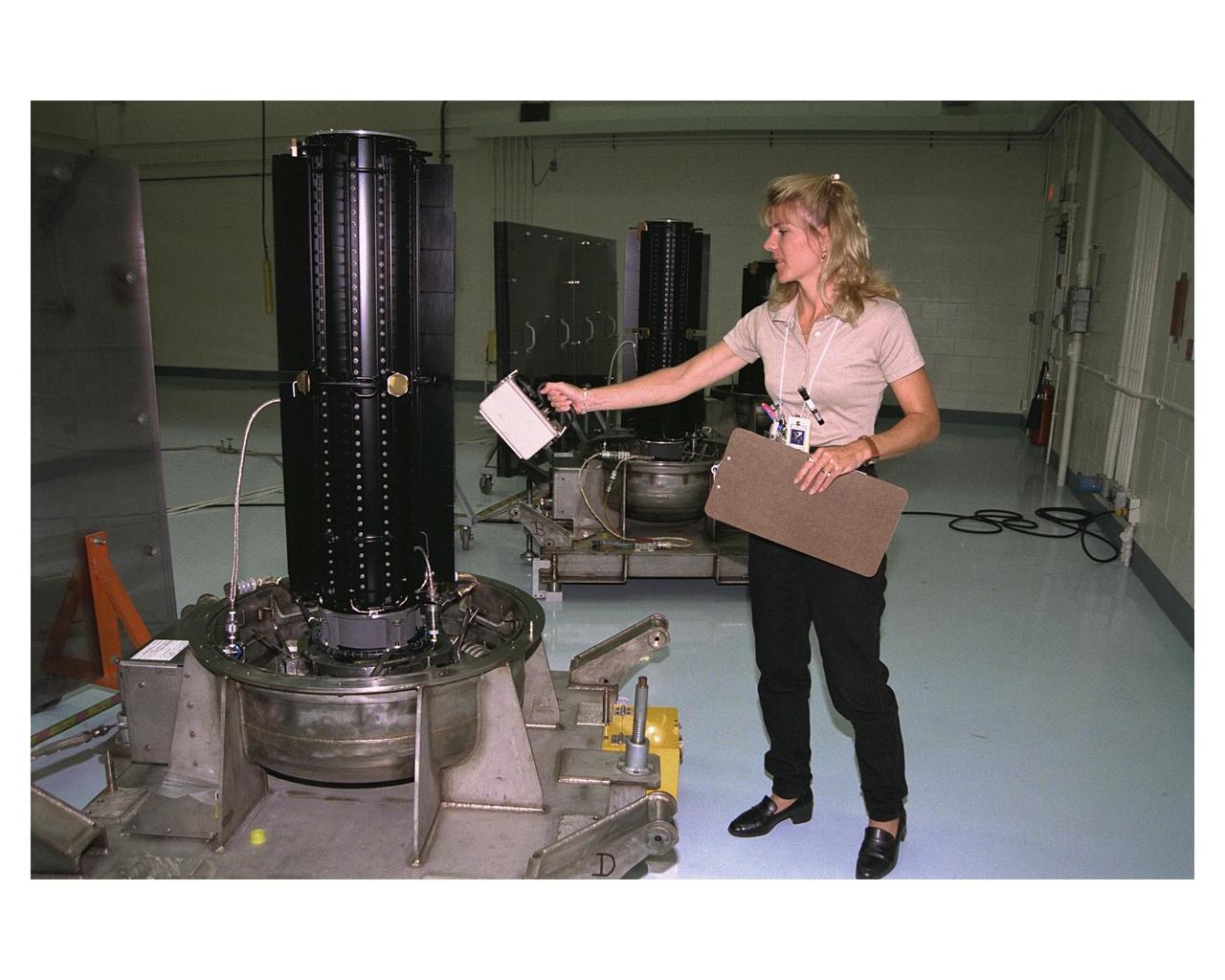Environmental Health Specialist Jamie A. Keeley, of EG&G Florida Inc., uses an ion chamber dose rate meter to measure radiation levels in one of three radioisotope thermoelectric generators (RTGs) that will provide electrical power to the Cassini spacecraft on its mission to explore the Saturnian system.  The three RTGs and one spare are being tested and mointored in the Radioisotope Thermoelectric Generator Storage Building in the KSC's Industrial Area.  The RTGs use heat from the natural decay of plutonium to generate electric power.  RTGs enable spacecraft to operate far from the Sun where solar power systems are not feasible.  The RTGs on  Cassini are of the same design as those flying on the already deployed Galileo and Ulysses spacecraft.  The Cassini mission is targeted for an Oct. 6 launch aboard a Titan IVB/Centaur expendable launch vehicle.