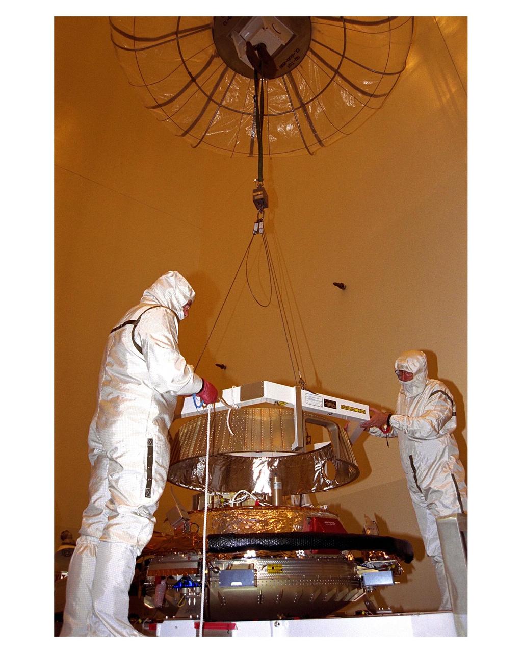 The aft shield is installed on the Huygens probe in the Payload Hazardous Servicing Facility (PHSF). The European Space Agency's Huygens probe will be attached to the Cassini spacecraft which will explore the Titan moon of the Saturnian system