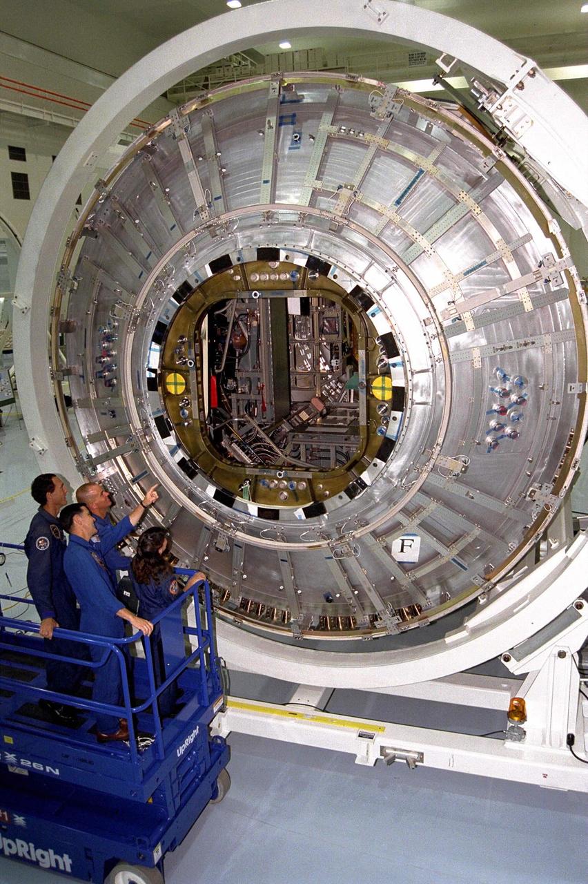Members of the STS-88 crew examine the Node 1 of the Internation Space Station in the high bay of the Space Station Processing Facility. The module is the first element of the International Space Station to be manufactured in the United States and the first scheduled to be launched on the Space Shuttle. The Node 1 is currently scheduled to lift off aboard the Space Shuttle Endeavour in July 1998, along with Pressurized Mating Adapters (PMAs) 1 and 2. The 18-foot-in-diameter, 22-foot-long aluminum module was manufactured by the Boeing Co. at Marshall Space Flight Center. Once in space, the Node 1 will function as a connecting passageway to the living and working areas of the International Space Station. The six hatches on the Node 1 will serve as docking ports to the U.S. laboratory module, U.S. habitation module, an airlock and other space station elements