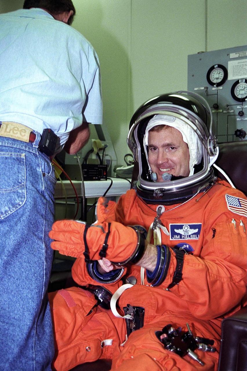 STS-94 Mission Commander James D. Halsell,  Jr.,  puts his left glove on while he is assisted into his launch/entry suit in the Operations  and Checkout (O&C) Building. Halsell is on his fourth space flight, having served as  commander of STS-83 and pilot of both  STS-74 and STS-65. He is a lieutenant colonel  in the Air Force  and a former SR-71 Blackbird test pilot and holds master’s degrees in  management and space operations. Halsell will have responsibility for the success of the  mission and will operate and maintain Columbia during the Red, or second shift. He will  also assist with a  materials science experiment and a protein crystal growth payload  during the 16-day mission. Halsell and six fellow crew members will shortly depart the  O&C and head for Launch Pad 39A, where the  Space Shuttle Columbia will lift off  during a launch window that opens at 1:50 p.m. EDT, July 1. The launch window was  opened 47 minutes early to improve the opportunity to lift off before Florida summer rain  showers reached the space center