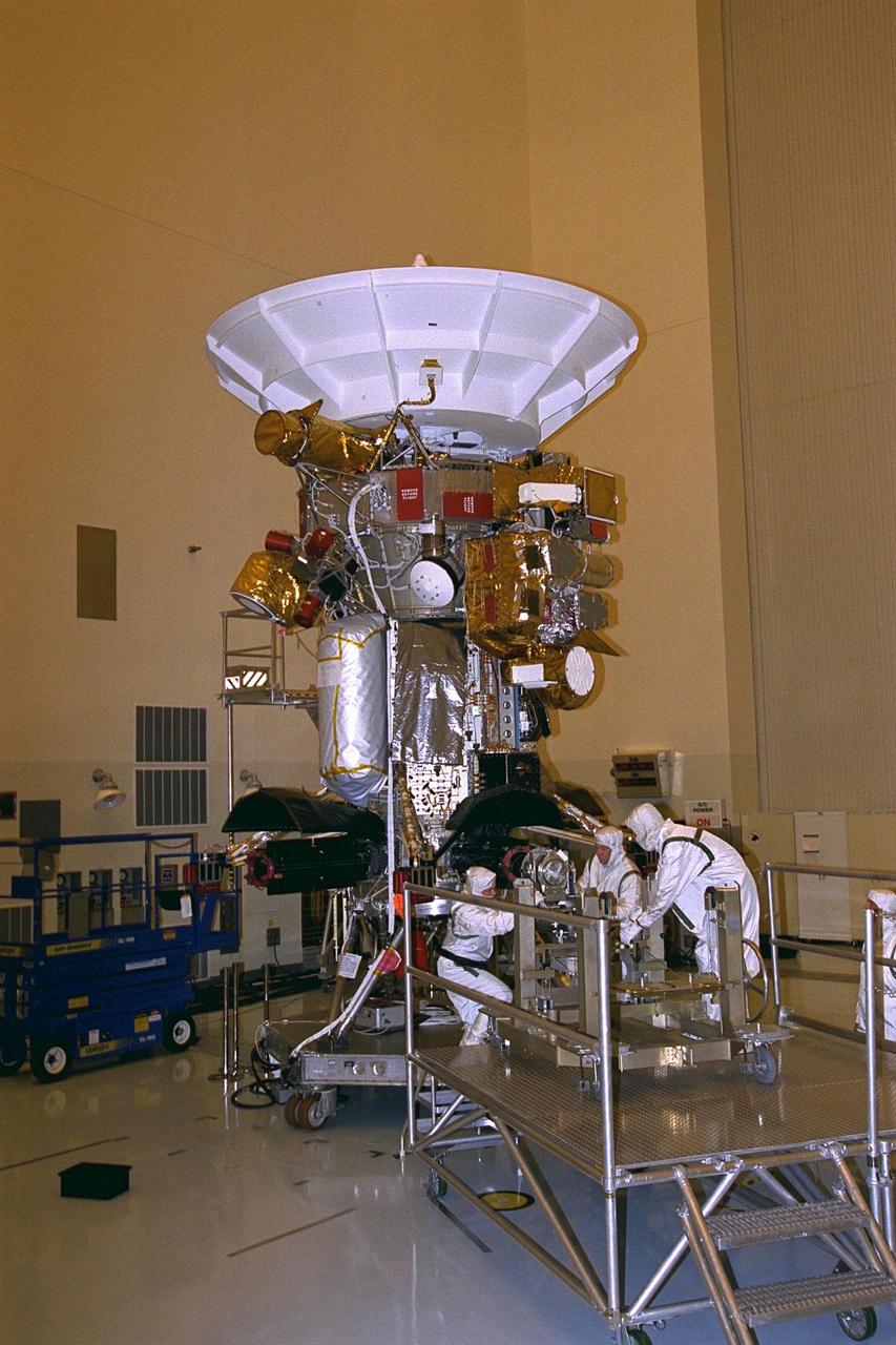 Jet Propulsion Laboratory (JPL) workers prepare the  installation cart (atop the platform) for removal of a radioisotope thermoelectric  generator (RTG) from the adjacent Cassini spacecraft. This is the second of three RTGs   being removed from Cassini after undergoing mechanical and electrical verification tests  in the Payload Hazardous Servicing Facility. The third RTG to be removed is in  background at left. The three RTGs will then be temporarily stored before being  re-installed for flight. The RTGs will provide electrical power to Cassini on its 6.7-year  trip to the Saturnian system and during its four-year mission at Saturn. RTGs use heat  from the natural decay of plutonium to generate electric power. The generators enable  spacecraft to operate far from the Sun where solar power systems are not feasible. The  Cassini mission is scheduled for an Oct. 6 launch aboard a Titan IVB/Centaur  expendable launch vehicle. Cassini is built and managed for NASA by JPL