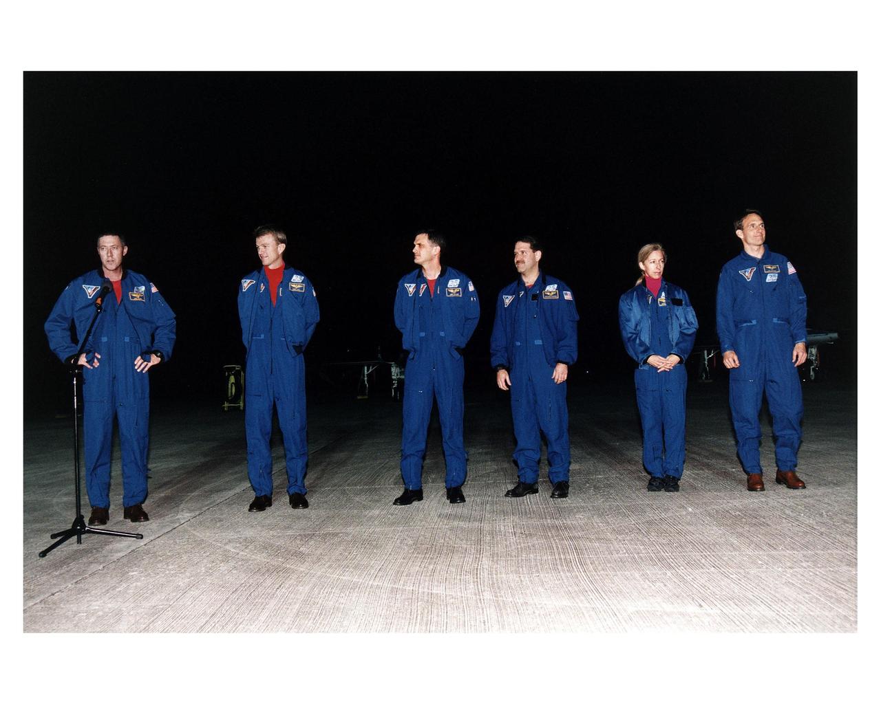 The STS-81 flight crew conducts a press briefing on the runway of KSC's Shuttle Landing Facility after they arrive at the space center for the final countdown preparations for the fifth Shuttle-Mir docking mission. They are (from left): Mission Commander Michael A. Baker; Pilot Brent W. Jett, Jr.; and Mission Specialists Peter J. K. "Jeff" Wisoff; John M. Grunsfeld, Marsha S. Ivins, and J.M. "Jerry" Linenger. The 10-day mission will feature the transfer of Linenger to Mir to replace astronaut John Blaha, who has been on the orbital laboratory since Sept. 19, 1996 after arrival there during the STS79 mission. During STS-81, Shuttle and Mir crews will conduct risk mitigation, human life science, microgravity and materials processing experiments that will provide data for the design, development and operation of the International Space Station. The primary payload is the SPACEHAB-DM double module which will provide space for more than 2,000 pounds of hardware, food and water that will be transferred into the Russian space station during five days of docking operations. The SPACEHAB will also be used to return experiment samples from the Mir to Earth for analysis and for microgravity experiments during the mission