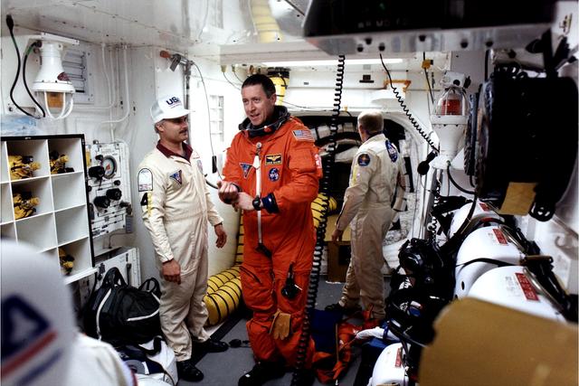 NASA image: KENNEDY SPACE CENTER, FLA. -  STS-81 Mission Commander Michael Baker prepares to enter the Space Shuttle Atlantis at Launch Pad 39B with help from White Room closeout crew members Chris Meinert (left) and Danny Wyatt.