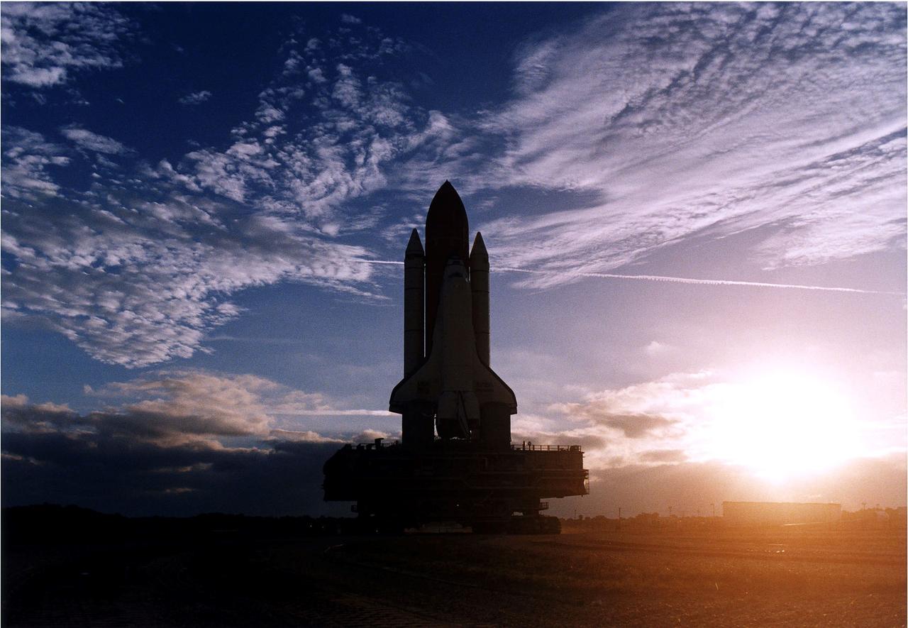KENNEDY SPACE CENTER, FLA. -  The rising sun and some scattered clouds provide a picturesque backdrop for the Space Shuttle Discovery as it travels along the crawlerway toward Launch Pad 39A in preparation for the STS-82 mission.  The Shuttle is on a Mobile Launcher Platform, and the entire assemblage is being carried by a large, tracked vehicle called the crawler transporter.  A seven-member crew will perform the second servicing of the orbiting Hubble Space Telescope (HST) during the 10-day STS-82 flight, whcih is targeted for a Feb. 11 liftoff.