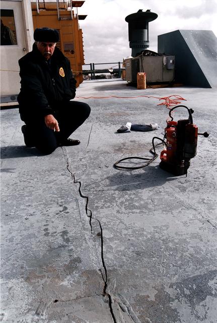 NASA image: KENNEDY SPACE CENTER, FLA. -  Robert T. Nelson of KSC Security points to an approximately 24-foot-long crack on the Mobile Launcher Platform (MLP), which is holding the Space Shuttle Discovery en route to Launch Pad 39A for the STS-82 mission.  Nelson was riding on the MLP when he heard a loud noise and noticed the crack.  Rollout had begun shortly after 7 a.m. EST and was stopped at about 8:25 a.m.  This Y-shaped crack is on the MLP surface and runs from near the left-hand solid rocket booster flame hole toward the near corner of the MLP.  Rollout of Discovery resumed just past noon after structural engineers determined that the integrity of the MLP had not been compromised.  Discovery is scheduled to lift off on the second Hubble Space Telescope servicing mission on Feb. 11.