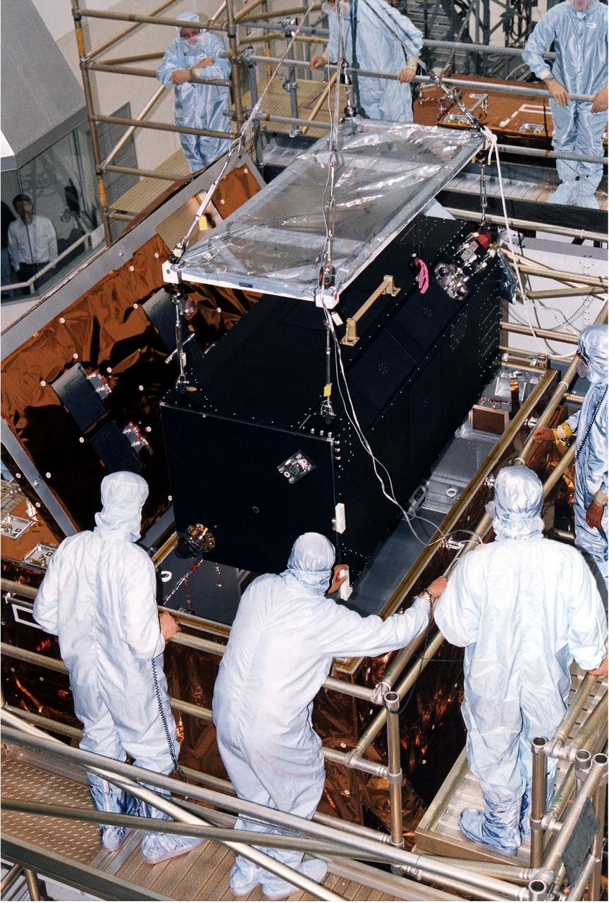 KENNEDY SPACE CENTER, FLA. - Workers in KSC's Vertical Processing Facility lower the Near Infrared Camera and Multi-Object Spectrometer (NICMOS) into the Second Axial Carrier.  NICMOS is one of two new scientific instruments that will replace two outdated instruments on the Hubble Space Telescope (HST).  NICMOS will provide HST with the capability for infrared imaging and spectroscopic observations of astronomical targets.  The refrigerator-sized NICMOS also is HST's first cryogenic instrument — its sensitive infrared detectors must operate at very cold temperatures of minus 355 degrees Fahrenheit or 58 degrees Kelvin.  NICMOS will be installed in Hubble during STS-82, the second Hubble Space Telescope servicing mission.  Liftoff is targeted Feb. 11 aboard Discovery with a crew of seven.