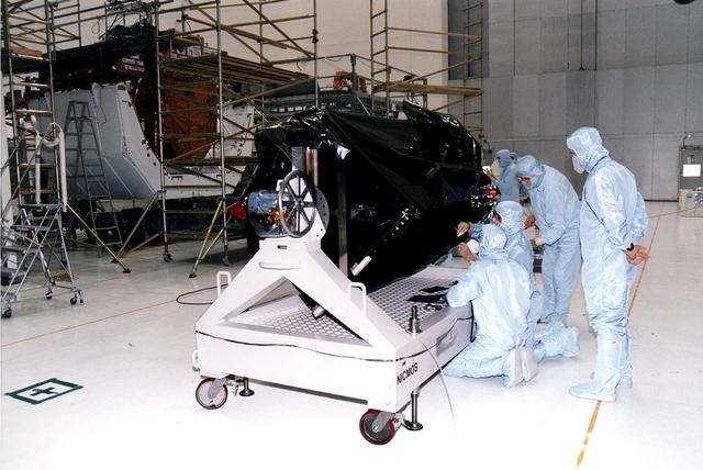 KENNEDY SPACE CENTER, FLA. - Workers in KSC's Vertical Processing Facility inspect the Near Infrared Camera and Multi-Object Spectrometer (NICMOS) on its handling fixture.  NICMOS is one of two new scientific instruments that will replace two outdated instruments on the Hubble Space Telescope (HST).  NICMOS will provide HST with the capability for infrared imaging and spectroscopic observations of astronomical targets.  The refrigerator-sized NICMOS also is HST's first cryogenic instrument — its sensitive infrared detectors must operate at very cold temperatures of minus 355 degrees Fahrenheit or 58 degrees Kelvin.  NICMOS will be installed in Hubble during STS-82, the second Hubble Space Telescope servicing mission.  Liftoff is targeted Feb. 11 aboard Discovery with a crew of seven.
