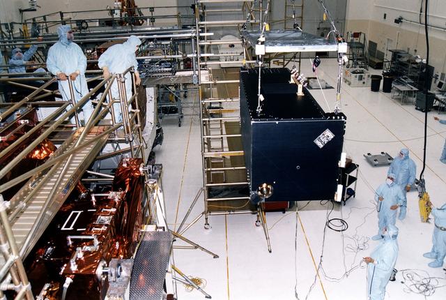 NASA image: KENNEDY SPACE CENTER, FLA. - Workers in KSC's Vertical Processing Facility lift the Near Infrared Camera and Multi-Object Spectrometer (NICMOS) prior to its installation in the Second Axial Carrier.  NICMOS is one of two new scientific instruments that will replace two outdated instruments on the Hubble Space Telescope (HST).  NICMOS will provide HST with the capability for infrared imaging and spectroscopic observations of astronomical targets.  The refrigerator-sized NICMOS also is HST's first cryogenic instrument — its sensitive infrared detectors must operate at very cold temperatures of minus 355 degrees Fahrenheit or 58 degrees Kelvin.  NICMOS will be installed in Hubble during STS-82, the second Hubble Space Telescope servicing mission.  Liftoff is targeted Feb. 11 aboard Discovery with a crew of seven.