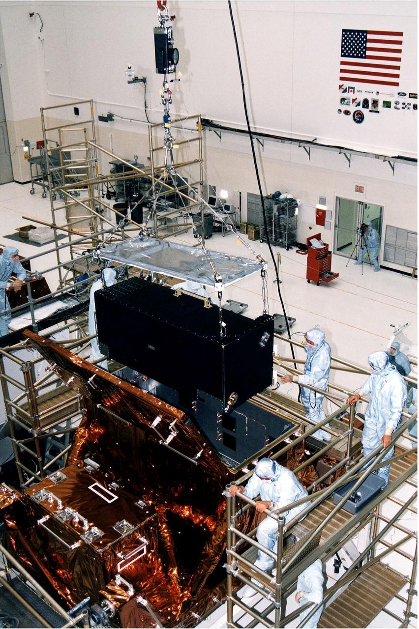 KENNEDY SPACE CENTER, FLA. -  Workers in KSC's Vertical Processing Facility lower the Near Infrared Camera and Multi-Object Spectrometer (NICMOS) into the Second Axial Carrier.  NICMOS is one of two new scientific instruments that will replace two outdated instruments on the Hubble Space Telescope (HST).  NICMOS will provide HST with the capability for infrared imaging and spectroscopic observations of astronomical targets.  The refrigerator-sized NICMOS is HST's first cryogenic instrument -- its sensitive infrared detectors must operate at very cold temperatures of minus 355 degrees Fahrenheit or 58 derees Kelvin.  NICMOS will be installed in Hubble during STS-82, the second Hubble Space Telescope servicing mission.  Liftoff is targeted Feb. 11 aboard Discovery with a crew of seven.