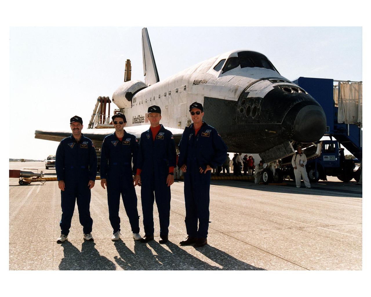 KENNEDY SPACE CENTER, FLA. -- Four members of the STS-81 crew pose in front of the Space Shuttle orbiter Atlantis on Runway 33 of KSC’s Shuttle Landing Facility after the space plane touched down at 9:22:44 a.m. EST Jan. 22 to conclude the fifth Shuttle-Mir docking mission. The crew members are (from left): Mission Specialists John M. Grunsfeld and Peter J. K. "Jeff" Wisoff ; Pilot Brent W. Jett, Jr.; and Mission Commander Michael A. Baker. Also returning on board Atlantis were Mission Specialist Marsha S. Ivins and John Blaha, who had been a member of the Mir 22 crew for four months. At main gear touchdown, the STS-81 mission duration was 10 days, 4 hours, 55 minutes. This was the 34th KSC landing in Shuttle history