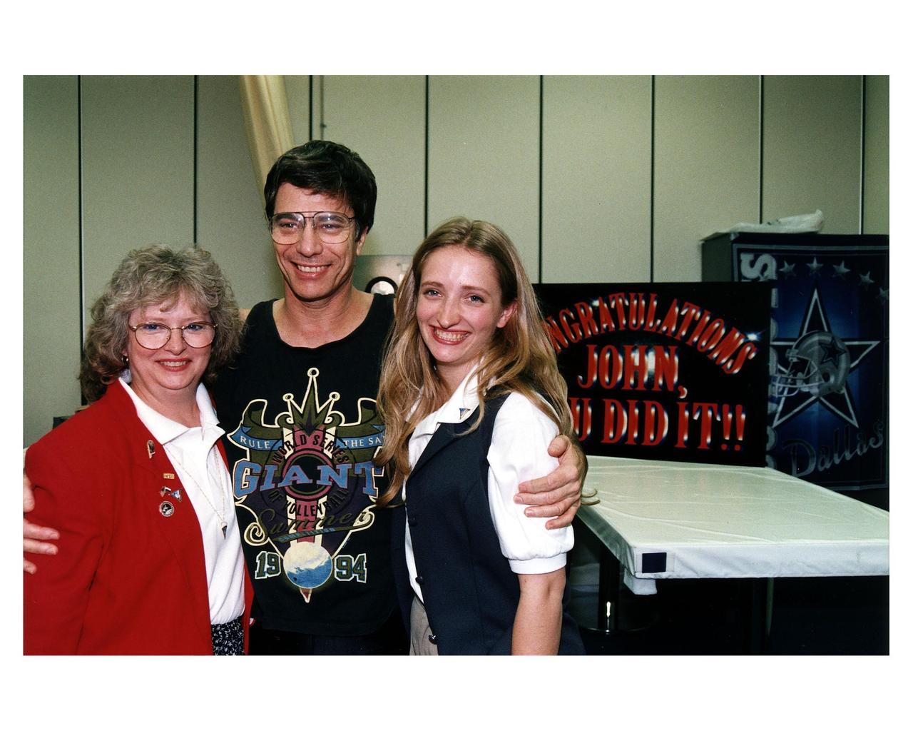 U. S. astronaut John E. Blaha and his family are all smiles as they embrace in the crew quarters at KSC after he answered questions about his four-month stay aboard the Russian Mir space station. Blaha’s wife, Brenda, is on the left and his daughter, Carolyn, is on the right. Blaha returned to Earth earlier today aboard the Space Shuttle orbiter Atlantis when it touched down at 9:22:44 a.m. EST Jan. 22 on Runway 33 of KSC’s Shuttle Landing Facility at the conclusion of the STS-81 mission. Blaha and the other five returning STS-81 crew members are spending the night here in the Operations and Checkout Building before returning to Johnson Space Center in Houston tomorrow morning. Blaha will undergo a two-week series of medical tests to help determine the physiological effects of his long-duration mission