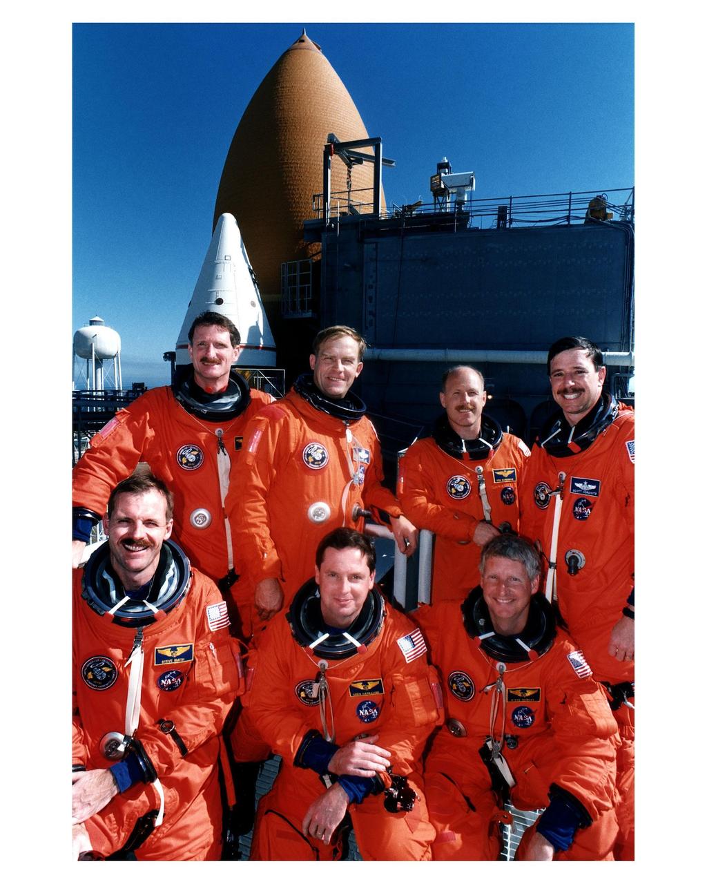 KENNEDY SPACE CENTER, FLA. -- STS-82 crew members are all smiles as they pose for a group photo at Launch Pad 39A in front of the Space Shuttle Discovery. They are participating in the Terminal Countdown Demonstration Test (TCDT), a dress rehearsal for launch. In the front row, from left, are Mission Specialists Steven L. Smith, Gregory J. Harbaugh and Steven A. Hawley. Standing in the back row, from left, are Joseph R. "Joe" Tanner, Payload Commander Mark C. Lee, Mission Commander Kenneth D. Bowersox and Pilot Scott J. "Doc" Horowitz. STS-82 will be the second Hubble Space Telescope servicing mission. Liftoff is targeted for Feb. 11