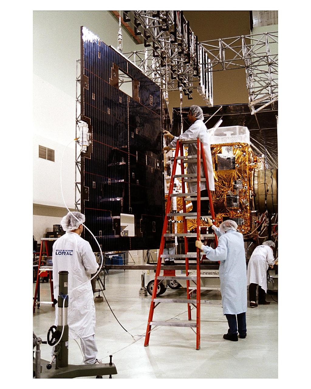 Space Systems/LORAL employees inspect solar panels for the GOES-K weather satellite in the Astrotech facility at Titusville, Fla., as they begin final testing of the imaging system, communications and power systems of the spacecraft. The GOES-K is the third spacecraft to be launched in the new advanced series of geostationary weather satellites for the National Oceanic and Atmospheric Administration (NOAA). The GOES-K is built for NASA and NOAA by Space Systems/LORAL of Palo Alto, Calif. The launch of the satellite from Launch Pad 36B at Cape Canaveral Air Station on an Atlas 1 rocket (AC-79) is currently planned for Apr. 24 at the opening of a launch window which extends from 1:56 to 3:19 a.m. EDT