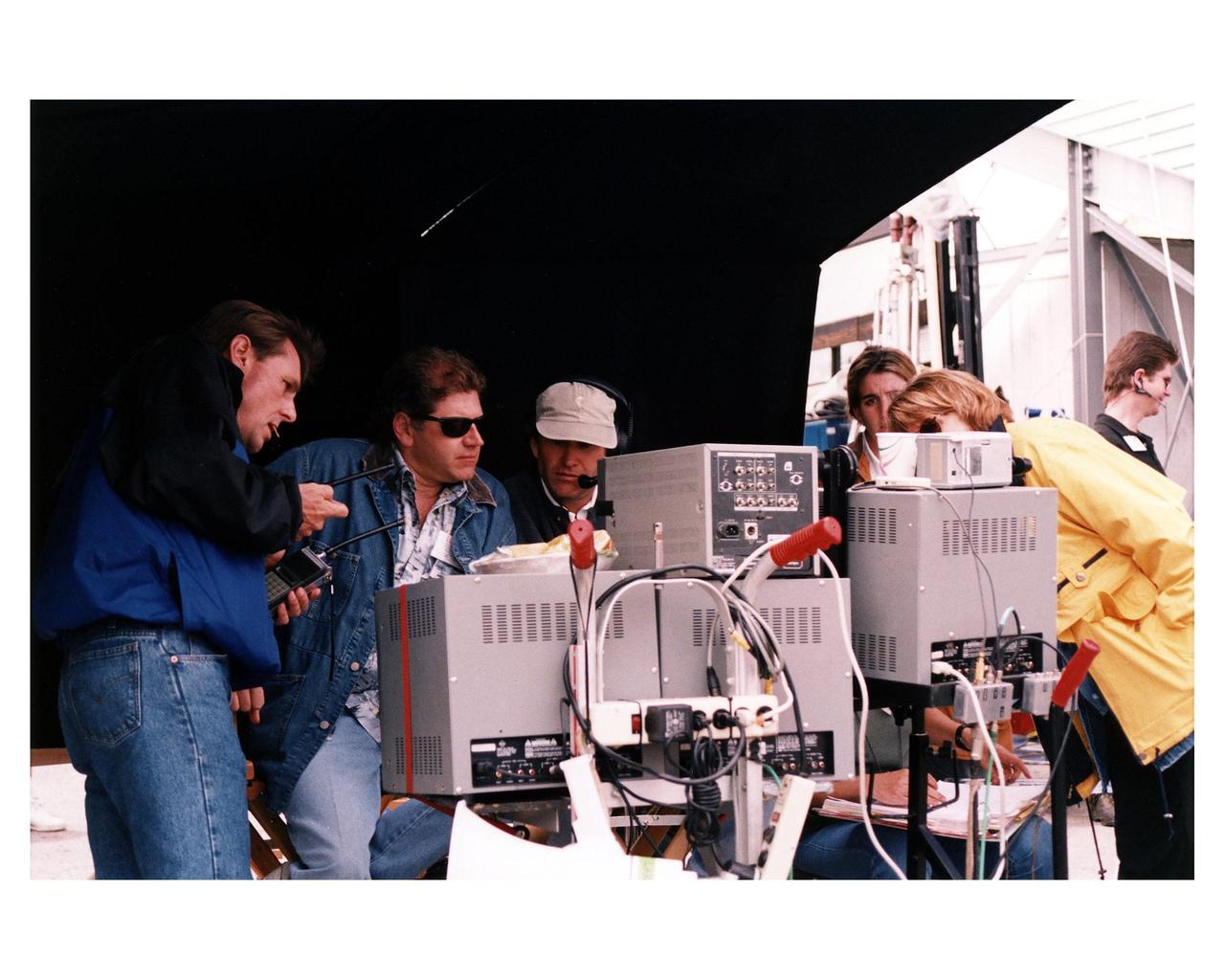 From left, Bruce Moriarty, first assistant director; Robert Zemeckis, director/producer; Don Burgess, director of photography; and other Warner Bros. crew members oversee the filming of scenes for the movie "Contact" at Kennedy Space Center's Launch Complex 39 Press Site on January 29. The screenplay for "Contact" is based on the best-selling novel by the late astronomer Carl Sagan. The cast includes Jodie Foster, Matthew McConaughey, John Hurt, James Woods, Tom Skerritt, David Morse, William Fichtner, Rob Lowe and Angela Bassett. Described by Warner Bros. as a science fiction drama, "Contact" will depict humankind's first encounter with evidence of extraterrestrial life