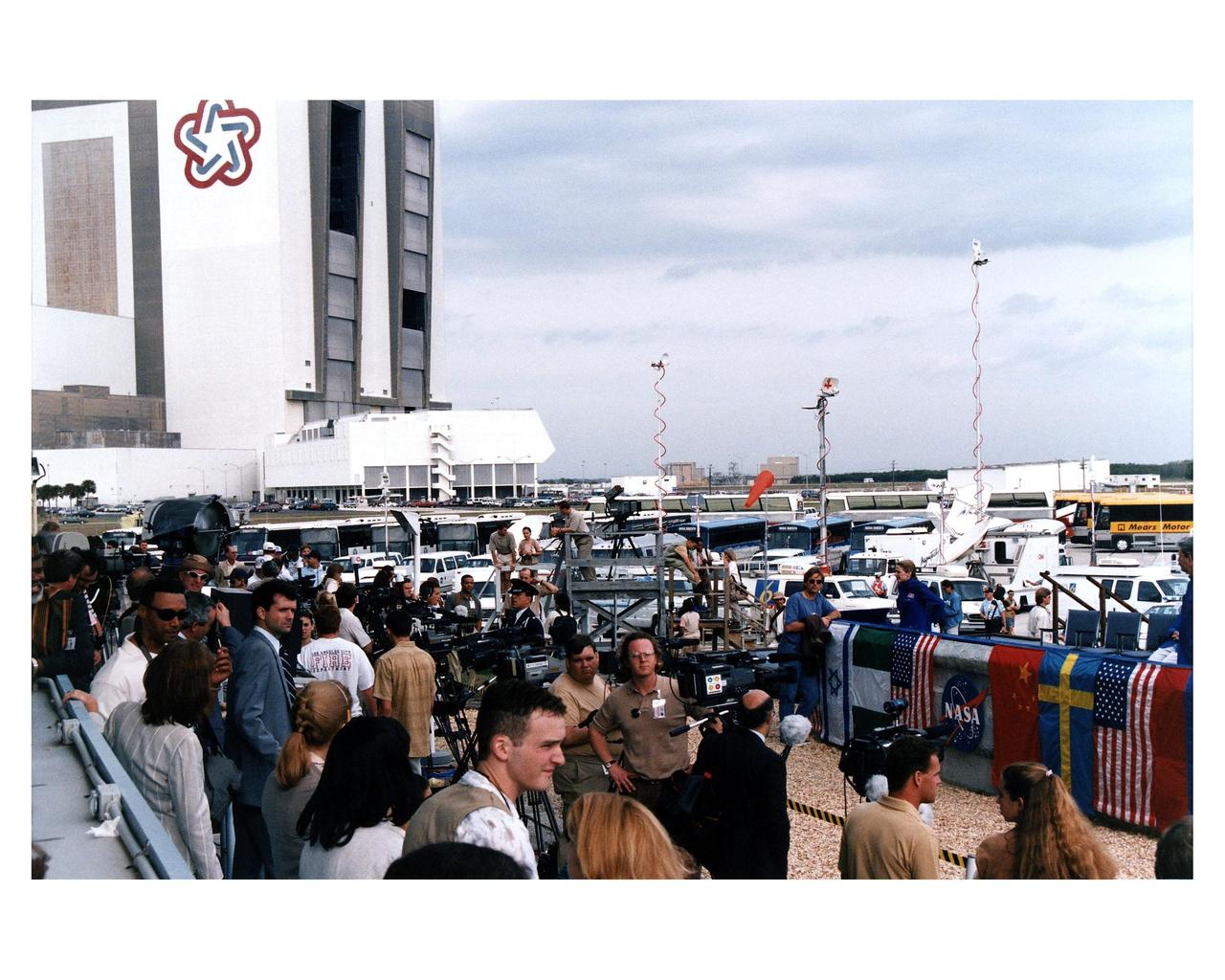 With the Vehicle Assembly Building looming in the background, Warner Bros.' cast and crew are filming scenes for the movie "Contact" at Kennedy Space Center's Launch Complex 39 Press Site on January 29. The screenplay for "Contact" is based on the best-selling novel by the late astronomer Carl Sagan. The cast includes Jodie Foster, Matthew McConaughey, John Hurt, James Woods, Tom Skerritt, David Morse, William Fichtner, Rob Lowe and Angela Bassett. Described by Warner Bros. as a science fiction drama, "Contact" will depict humankind's first encounter with evidence of extraterrestrial life