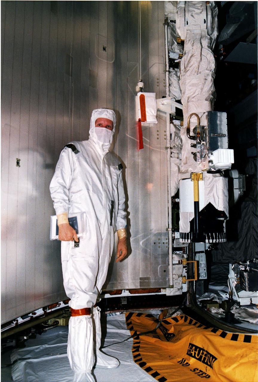 KENNEDY SPACE CENTER, FLA. -   STS-82 Mission Specialist Steven A Hawley stands beside part of Discovery's Remote Manipulator System (RMS) arm, at right, which he will operate for the capture, berthing and redeployment of the Hubble Space Telescope (HST).  The robotic arm also will be used as work platform for the four spacewalkers.  Hawley is the prime RMS operator on the flight, which will be the second HST servicing mission.  He and the other six members of the crew are making a final inspection of the payload at Launch Pad 39A before launch. STS-82 is scheduled for liftoff on Feb. 11 during a 65-minute launch window that opens at 3:56 a.m. EST.