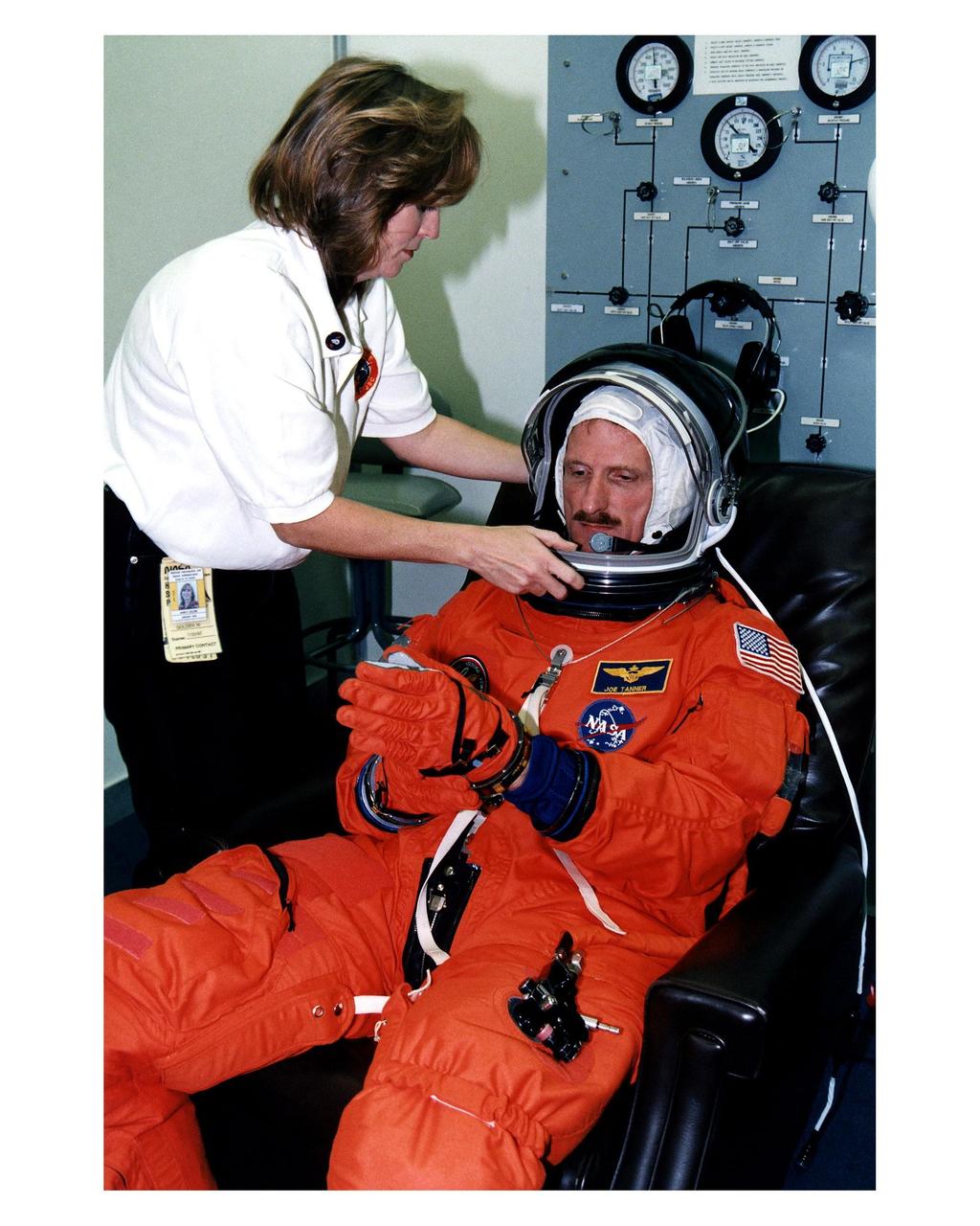 STS-82 Mission Specialist Joseph R. "Joe" Tanner dons his launch and entry suit in the Operations and Checkout Building with assistance from a suit technician. This is Tanner’s second space flight. He and the six other crew members will depart shortly for Launch Pad 39A, where the Space Shuttle Discovery awaits liftoff on a 10-day mission to service the orbiting Hubble Space Telescope (HST). This will be the second HST servicing mission. Four back-to-back spacewalks are planned