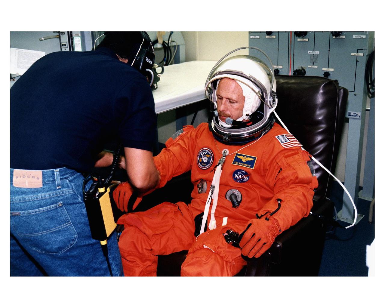 STS-82 Mission Commander Kenneth D. Bowersox makes some final adjustments to his launch and entry suit with assistance from a suit technician in the Operations and Checkout Building. This is his fourth space flight. He and the six other crew members will depart shortly for Launch Pad 39A, where the Space Shuttle Discovery awaits liftoff on a 10-day mission to service the orbiting Hubble Space Telescope (HST). This will be the second HST servicing mission. Four back-toback spacewalks are planned