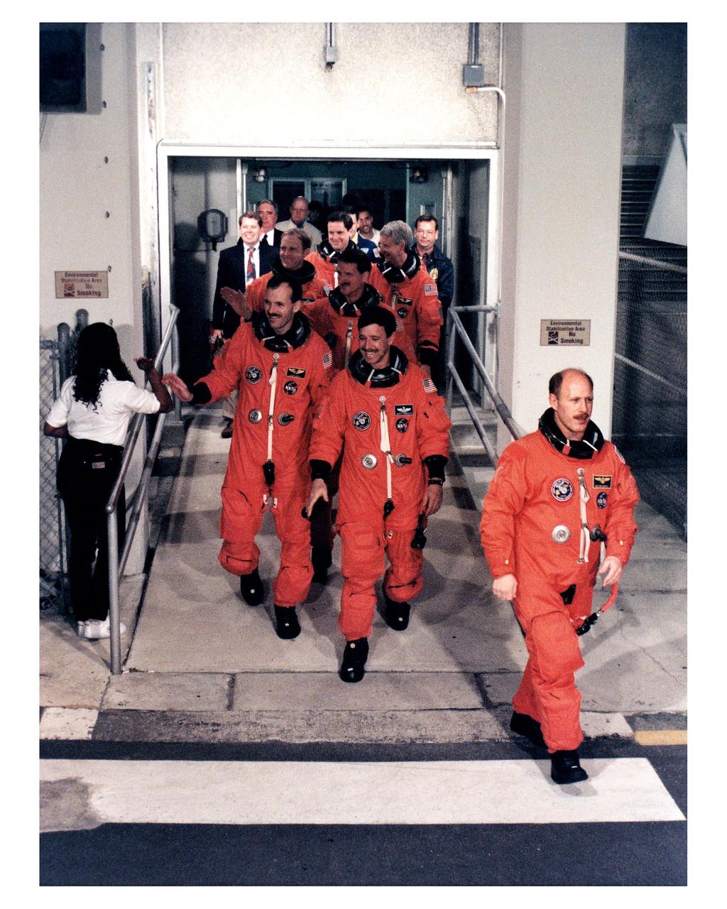 Looking relaxed and ready to fly, the STS-82 crew departs from the Operations and Checkout Building en route to Launch Pad 39A, where the Space Shuttle Discovery awaits liftoff on a 10-day mission to service the Hubble Space Telescope (HST). Leading the way is Mission Commander Kenneth D. Bowersox. Following him, clockwise from left front, are Mission Specialist Steven L. Smith, Payload Commander Mark C. Lee, Mission Specialists Gregory J. Harbaugh, Steven A. Hawley and Joseph R. "Joe" Tanner and Pilot Scott J. "Doc" Horowitz