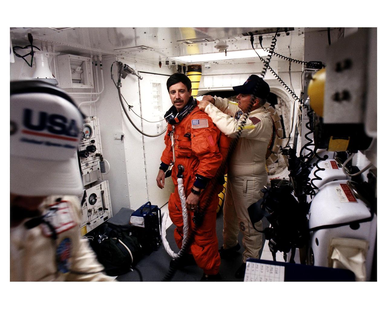 STS-82 Pilot Scott J. "Doc" Horowitz prepares to enter the Space Shuttle Discovery at Launch Pad 39A, with the assistance of white room closeout crew member James Davis