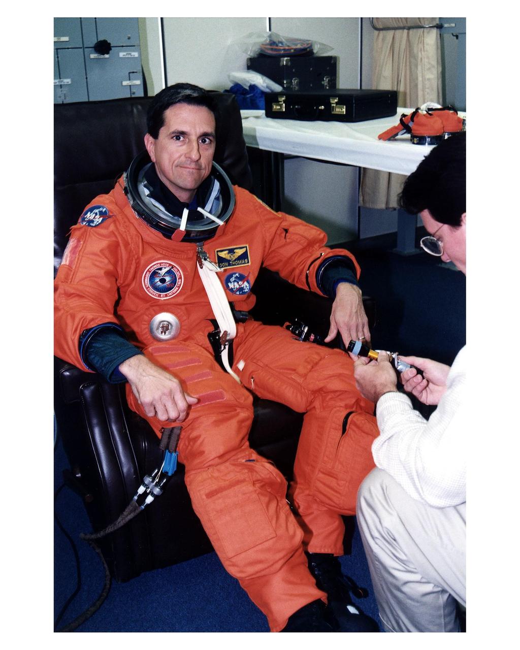 STS-83 Mission Specialist Donald A. Thomas is assisted into his launch/entry suit in the Operations and Checkout (O&C) Building. He has flown on both STS-70 and STS-65. He holds a doctorate in materials science and has been the Principal Investigator for a Space Shuttle crystal growth experiment. Because of his background in materials science, Thomas will be concentrating his efforts during the Red shift on the five experiments in this discipline in the large Isothermal Furnace. He also will work on the ten materials science investigations in the Electromagnetic Containerless Processing Facility and four that will be measuring the effects of microgravity and motion in the orbiter on the experiments. Thomas and six fellow crew members will shortly depart the O&C and head for Launch Pad 39A, where the Space Shuttle Columbia will lift off during a launch window that opens at 2:00 pm EST, April 4