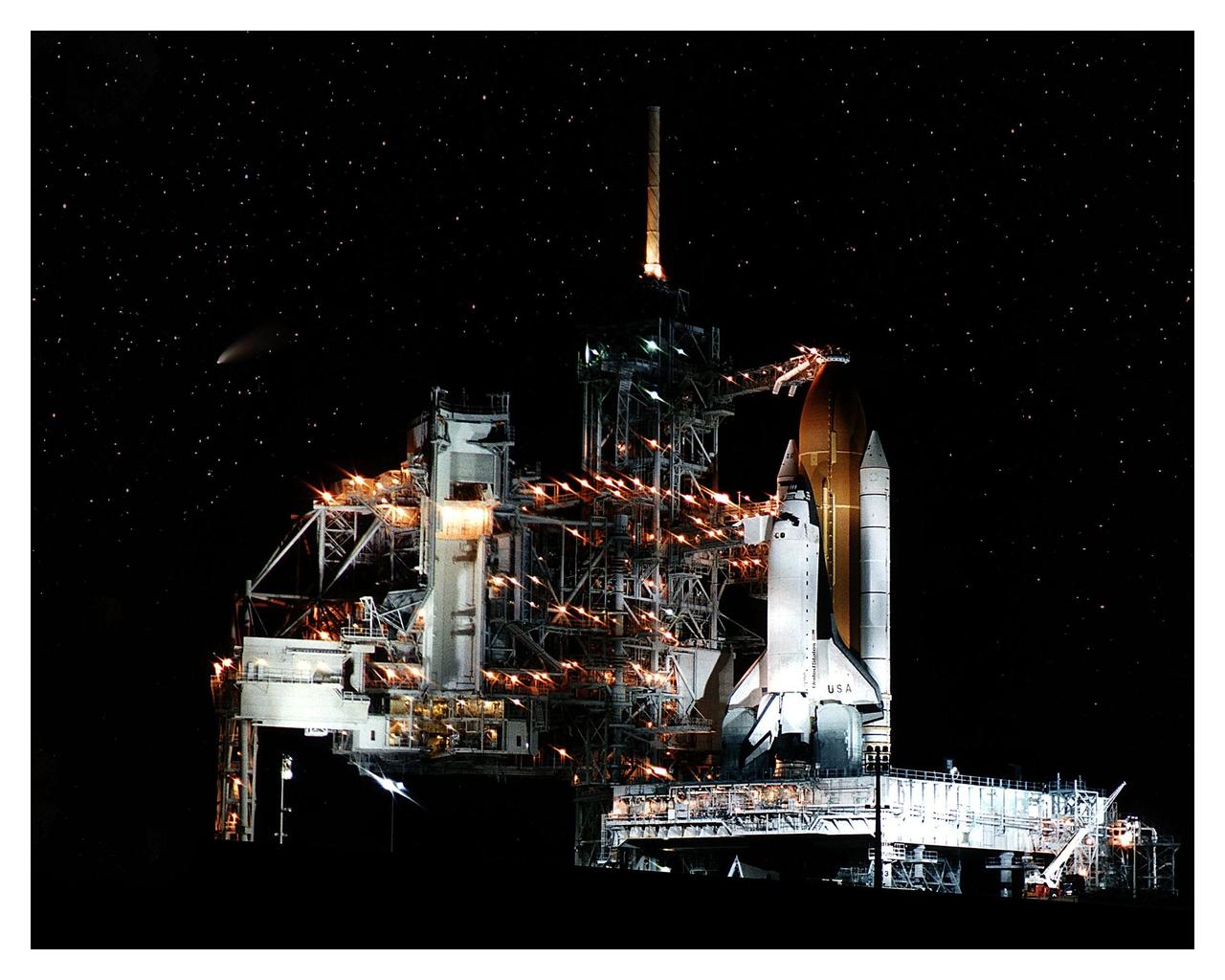 The soon-to-be-spaceborne Space Shuttle Columbia gets a flyby visit from the Comet Hale-Bopp (shown as the streak at left center) while awaiting launch on the STS-83 mission. This photo was taken the night before the planned liftoff on April 4, 1997. The Rotating Service Structure at Launch Pad 39A has been moved back prior to the start of operations to fuel the external tank. The primary objective of the STS-83 flight is to operate the Microgravity Science Laboratory-1 (MSL-1), which will test some of the hardware, facilities and procedures that will be used on the International Space Station. Columbia will have a crew of seven