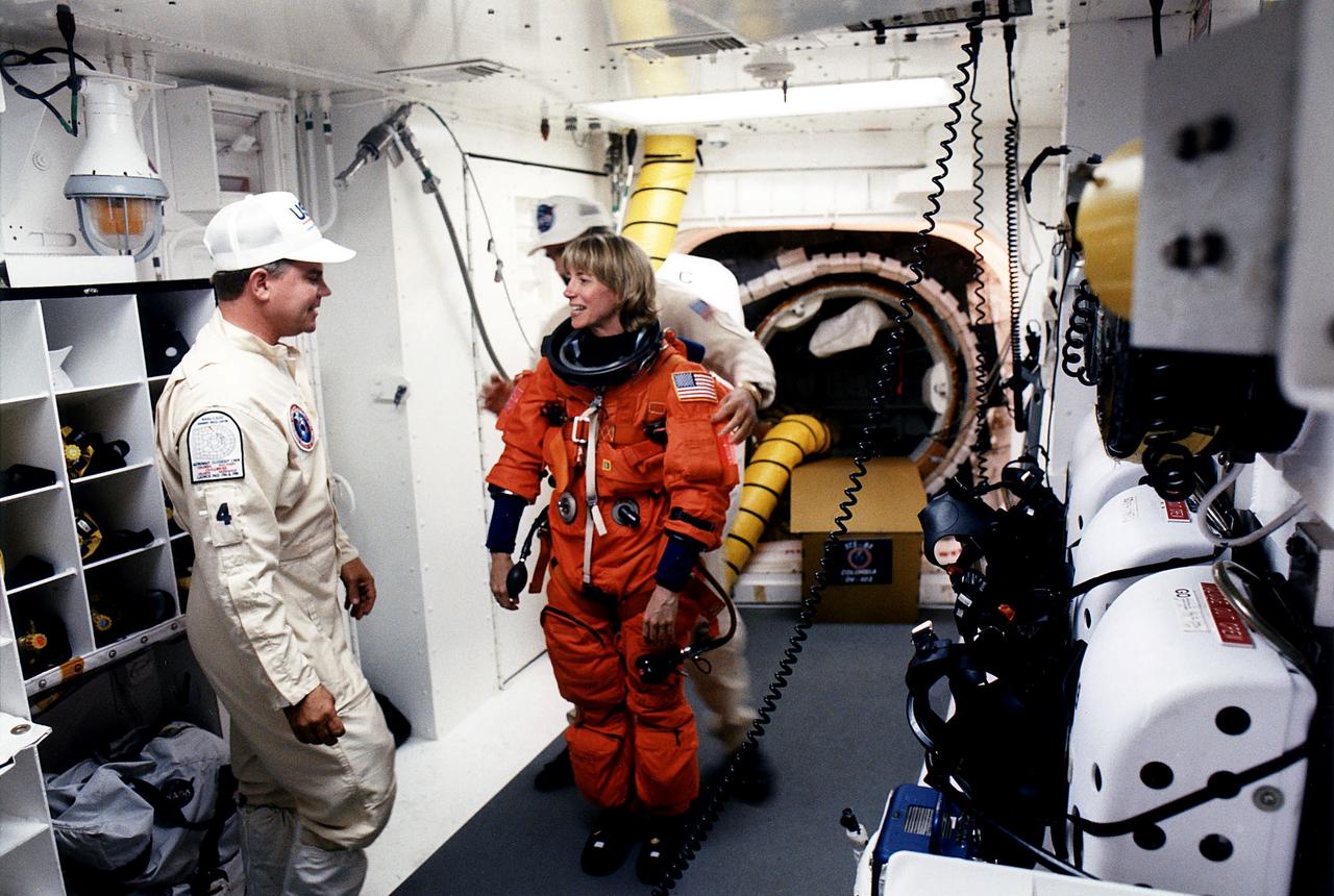 KENNEDY SPACE CENTER, FLA. - STS-83 Pilot Susan L. Still chats with White Room closeout crew member Rene Arriens as she prepares to enter the Space Shuttle Columbia at Launch Pad 39A with assistance from closeout crew worker Bob Saulnier (behind Still).