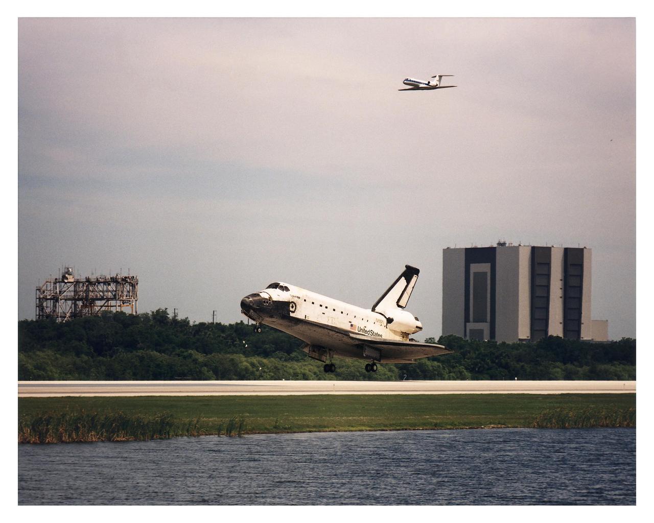 KENNEDY SPACE CENTER, FLA. -- The Space Shuttle Orbiter Columbia glides in for a touchdown on Runway 33 at KSC’s Shuttle Landing Facility that will conclude the Microgravity Science Laboratory-1 (MSL-1) mission. Columbia was scheduled to touch down at 2:33 p.m. EDT, April 8. The Vehicle Assembly Building (VAB) is to the right, while the Mate/Demate Device (MDD) is to the left. A NASA Shuttle Training Aircraft (STA) that acts as a chase plane during landings passes by overhead. With Columbia’s on-time main gear touchdown, the STS-83 mission duration will be 3 days, 23 hours, 12 minutes. The planned 16-day mission was cut short by a faulty fuel cell. This is only the third time in Shuttle program history that an orbiter was brought home early due to mechanical problems. This was also the 36th KSC landing since the program began in 1981