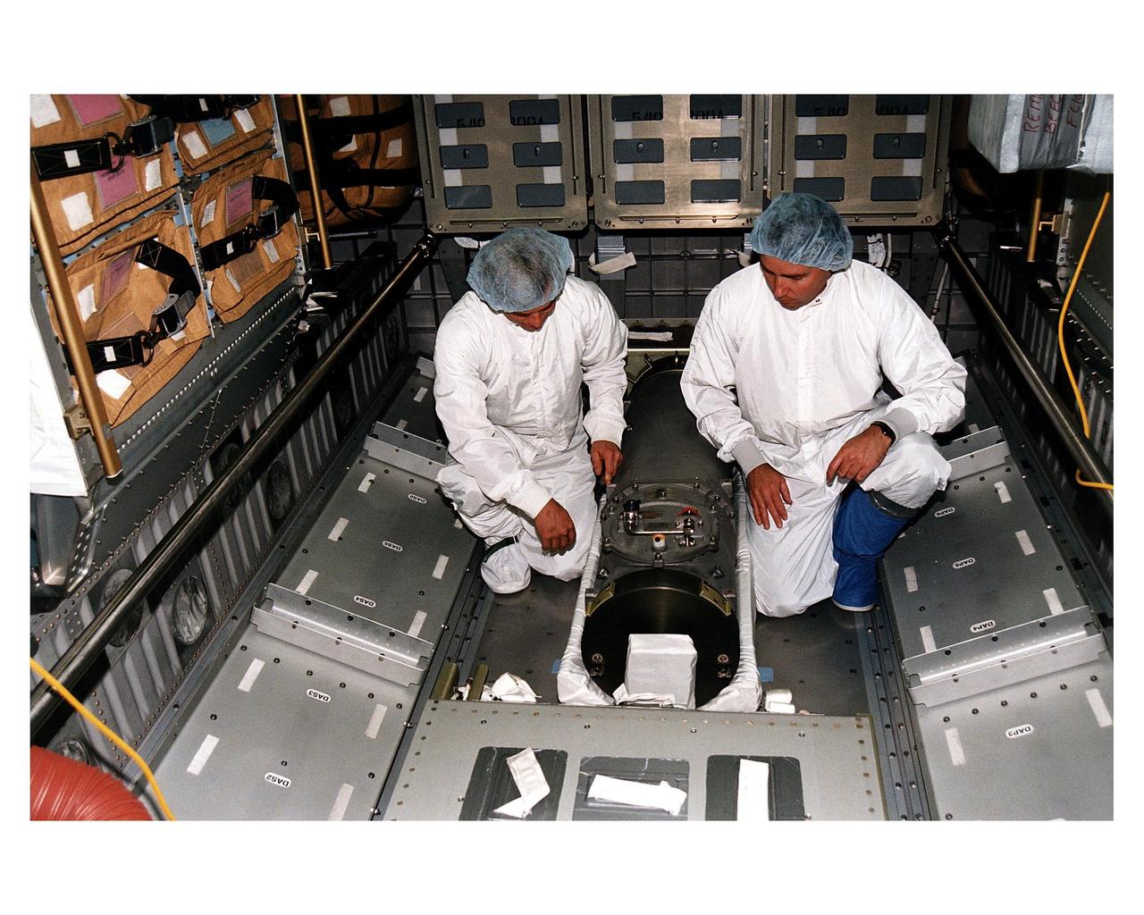 KENNEDY SPACE CENTER, FLA. -- McDonnell Douglas-SPACEHAB technicians look over a Russian-made oxygen generator which has just been placed on the floor of a SPACEHAB Double Module being prepared for flight on Space Shuttle Mission STS-84. The module is being processed in the SPACEHAB Payload Processing Facility just outside of Gate 1 on Cape Canaveral Air Station. The Space Shuttle Atlantis will transport the oxygen generator to the Russian Space Station Mir to replace one of two Mir units that have been malfunctioning recently. The nearly 300-pound generator functions by electrolysis, which separates water into its oxygen and hydrogen components. The hydrogen is vented and the oxygen is used for breathing by the Mir crew. The generator is 4.2 feet long with a diameter of 1.4 feet. STS-84, which is planned to include a Mir crew exchange of astronaut C. Michael Foale for Jerry M. Linenger, is targeted for a May 15 launch. It will be the sixth Shuttle-Mir docking
