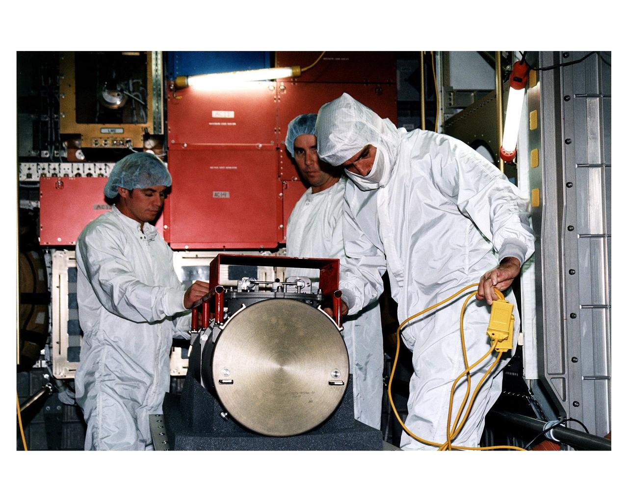 KENNEDY SPACE CENTER, FLA. -- McDonnell Douglas-SPACEHAB technicians prepare to place a Russian-made oxygen generator into position for transport in a SPACEHAB Double Module being processed for flight on Space Shuttle Mission STS-84. The module is undergoing preflight preparations in the SPACEHAB Payload Processing Facility just outside of Gate 1 on Cape Canaveral Air Station. The Space Shuttle Atlantis will carry the oxygen generator to the Russian Space Station Mir to replace one of two Mir units that have been malfunctioning recently. The nearly 300-pound generator functions by electrolysis, which separates water into its oxygen and hydrogen components. The hydrogen is vented and the oxygen is used for breathing by the Mir crew. The generator is 4.2 feet long with a diameter of 1.4 feet. STS-84, which is planned to include a Mir crew exchange of astronaut C. Michael Foale for Jerry M. Linenger, is targeted for a May 15 launch. It will be the sixth Shuttle-Mir docking
