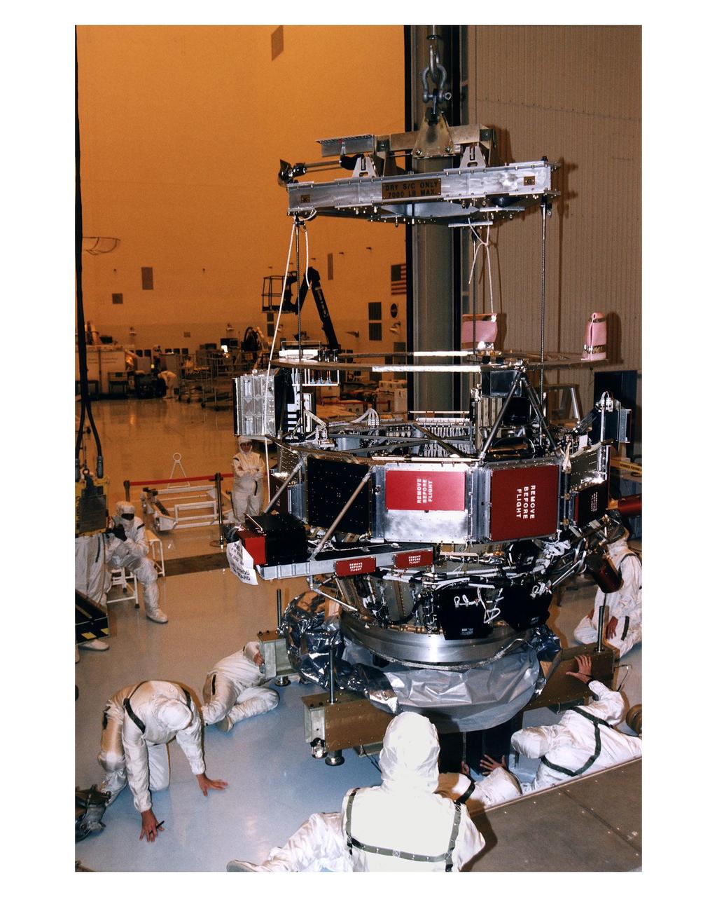Employees in the Payload Hazardous Servicing Facility (PHSF) lower the upper experiment module and base of the Cassini orbiter onto a work stand during prelaunch processing, testing and integration work in that facility. The Cassini orbiter and Huygens probe being processed at KSC are the two primary components of the Cassini spacecraft, which will be launched on a Titan IVB/Centaur expendable launch vehicle from Cape Canaveral Air Station. Cassini will explore Saturn, its rings and moons for four years. The Huygens probe, designed and developed for the European Space Agency (ESA), will be deployed from the orbiter to study the clouds, atmosphere and surface of Saturn’s largest moon, Titan. The orbiter was designed and assembled at NASA’s Jet Propulsion Laboratory in California. Following postflight inspections, integration of the 12 science instruments not already installed on the orbiter will be completed. Then, the parabolic high-gain antenna and the propulsion module will be mated to the orbiter, followed by the Huygens probe, which will complete spacecraft integration. The Cassini mission is targeted for an Oct. 6 launch to begin its 6.7-year journey to the Saturnian system. Arrival at the planet is expected to occur around July 1, 2004