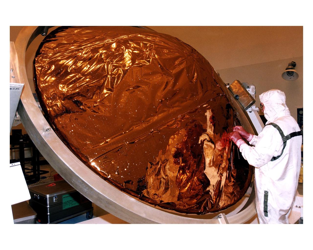 An employee in the Payload Hazardous Servicing Facility (PHSF) sews thermal insulation material on the back cover and heat shield of the Huygens probe during prelaunch processing, testing and integration in that facility. The Huygens probe and the Cassini orbiter being processed at KSC are the two primary components of the Cassini spacecraft, which will be launched on a Titan IVB/Centaur expendable launch vehicle from Cape Canaveral Air Station. Cassini will explore Saturn, its rings and moons for four years. The Huygens probe, designed and developed for the European Space Agency (ESA), will be deployed from the orbiter to study the clouds, atmosphere and surface of Saturn’s largest moon, Titan. The orbiter was designed and assembled at NASA’s Jet Propulsion Laboratory in California. Following postflight inspections, integration of the 12 science instruments not already installed on the orbiter will be completed. Then, the parabolic high-gain antenna and the propulsion module will be mated to the orbiter, followed by the Huygens probe, which will complete spacecraft integration. The Cassini mission is targeted for an Oct. 6 launch to begin its 6.7-year journey to the Saturnian system. Arrival at the planet is expected to occur around July 1, 2004
