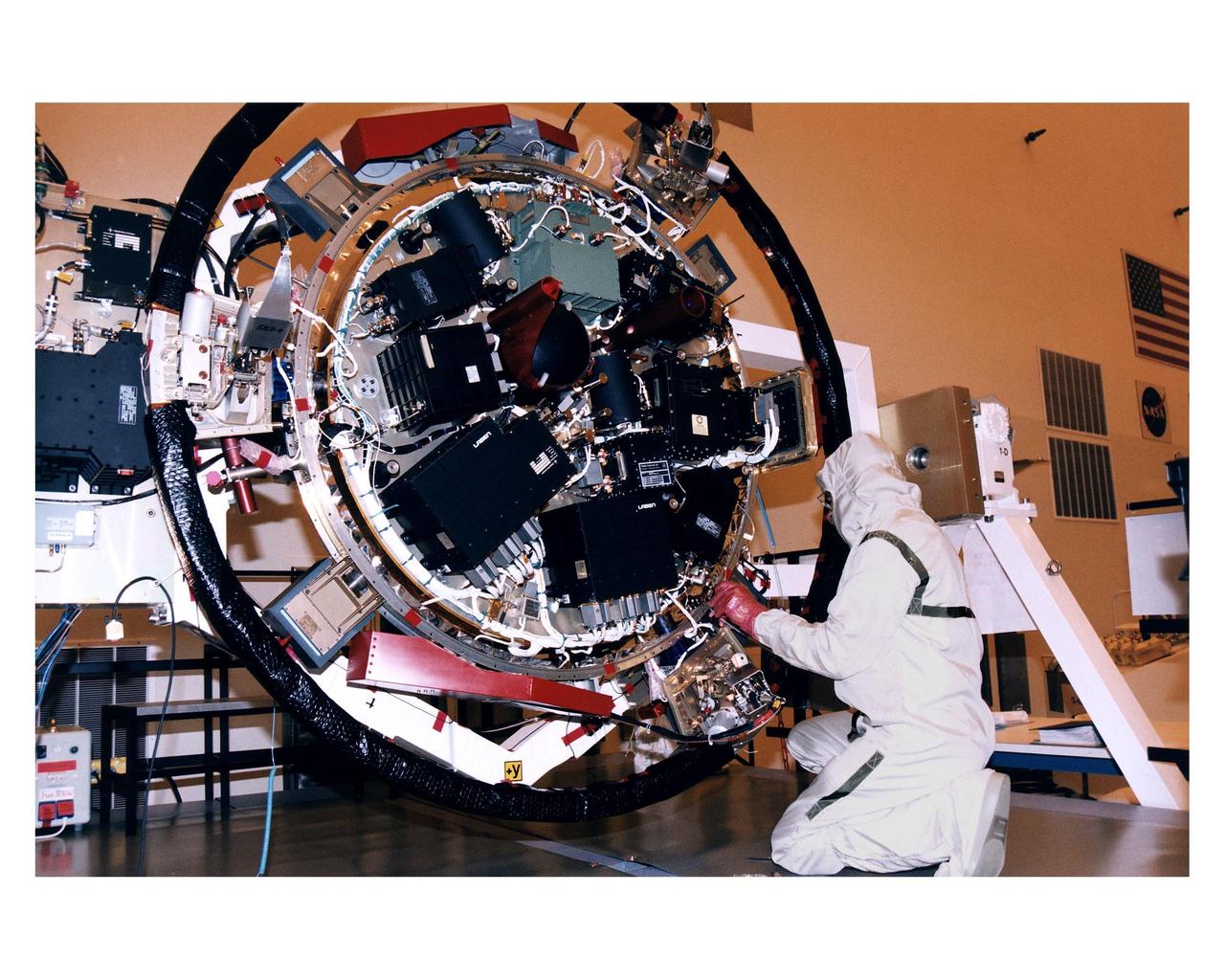 An employee in the Payload Hazardous Servicing Facility (PHSF) works on the top side of the experiment platform for the Huygens probe that will accompany the Cassini orbiter to Saturn during prelaunch processing, testing and integration in that facility. The Huygens probe and the Cassini orbiter being processed at KSC are the two primary components of the Cassini spacecraft, which will be launched on a Titan IVB/Centaur expendable launch vehicle from Cape Canaveral Air Station. Cassini will explore Saturn, its rings and moons for four years. The Huygens probe, designed and developed for the European Space Agency (ESA), will be deployed from the orbiter to study the clouds, atmosphere and surface of Saturn’s largest moon, Titan. The orbiter was designed and assembled at NASA’s Jet Propulsion Laboratory in California. Following postflight inspections, integration of the 12 science instruments not already installed on the orbiter will be completed. Then, the parabolic high-gain antenna and the propulsion module will be mated to the orbiter, followed by the Huygens probe, which will complete spacecraft integration. The Cassini mission is targeted for an Oct. 6 launch to begin its 6.7-year journey to the Saturnian system. Arrival at the planet is expected to occur around July 1, 2004