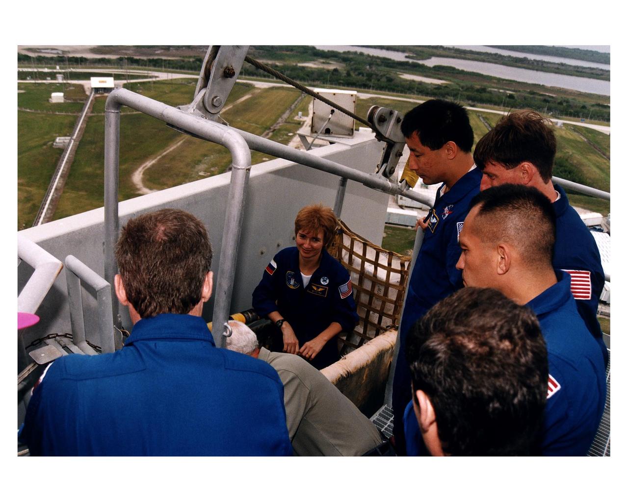 With several of her fellow crew members watching, STS-84 Mission Specialist Elena V. Kondakova, seated at center, gets instructions on using the slidewire baskets, part of the emergency egress system at Launch Pad 39A. Familiarization with pad procedures and systems is part of the Terminal Countdown Demonstration Test (TCDT) activities for the crew. Kondakova, a cosmonaut with the Russian space agency, is one of the seven STS-84 crew members for the sixth docking of the Space Shuttle with the Russian Space Station Mir. Another member, C. Michael Foale, will transfer to the space station and become a member of the Mir 23 crew, replacing U.S. astronaut Jerry M. Linenger, who will return to Earth aboard Atlantis. Foale will live and work on Mir until mid-September when his replacement is expected to arrive on the STS-86 mission. Kondakova previously lived on the Russian space station as the flight engineer of the 17th main mission on Mir from Oct. 4, 1994, to March 9, 1995. STS-84 is targeted for a May 15 liftoff