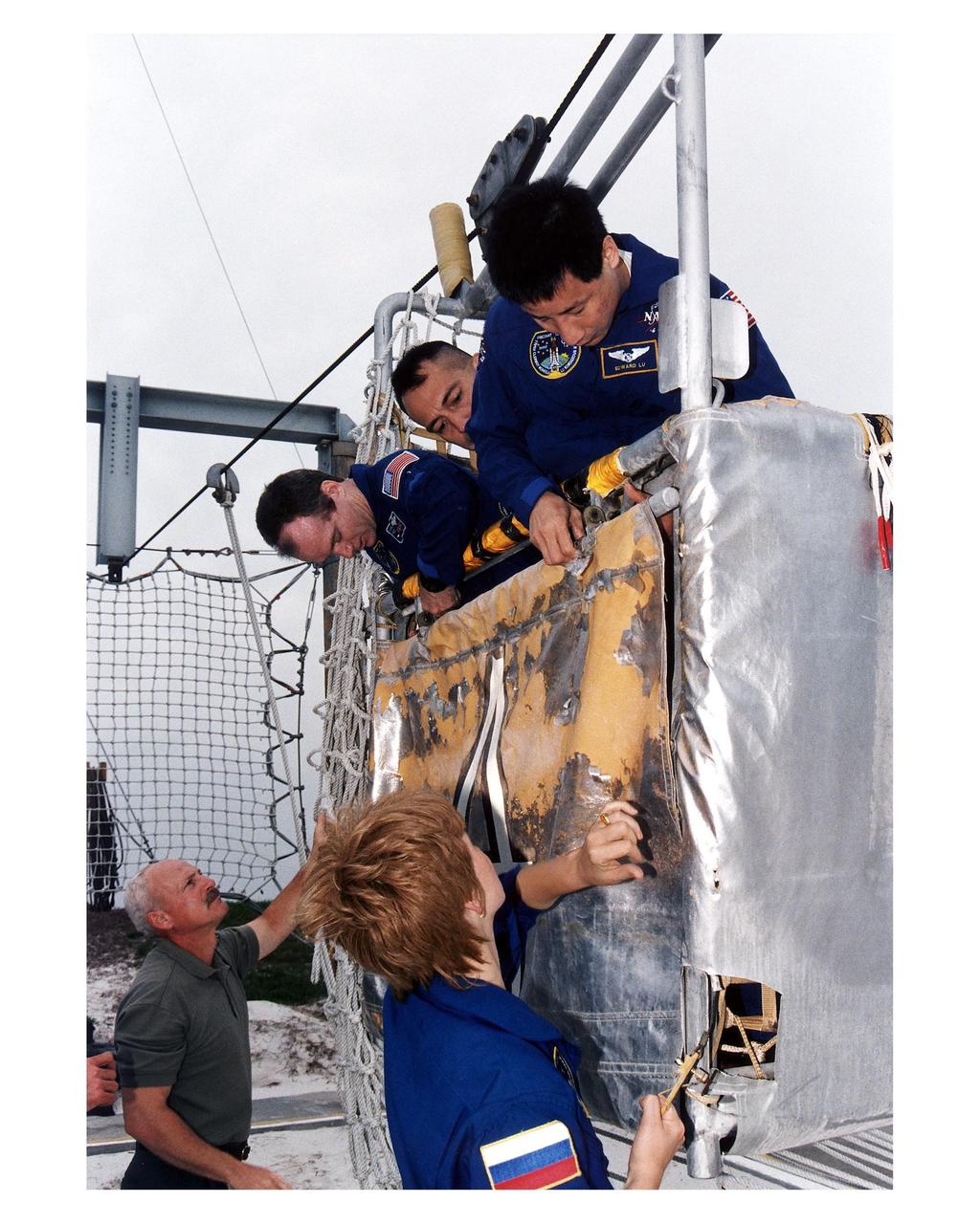 STS-84 crew members examine part of the emergency egress system at Launch Pad 39A, during Terminal Countdown Demonstration Test (TCDT) activities. Dressed in their blue flight suits are Mission Specialist Elena V. Kondakova, standing in foreground; and, in basket from right, Mission Specialists Edward Tsang Lu and Carlos I. Noriega and Commander Charles J. Precourt. Ken Clark, a training instructor with United Space Alliance (USA), is standing at lower left. STS-84 will be the sixth docking of the Space Shuttle with the Russian Space Station Mir. After docking, STS-84 Mission Specialist Michael C. Foale will transfer to the space station and become a member of the Mir 23 crew, replacing U.S. astronaut Jerry M. Linenger, who will return to Earth aboard Atlantis. Foale will live and work on Mir until mid-September when his replacement is expected to arrive on the STS-86 mission. STS-84 is targeted for a May 15 liftoff