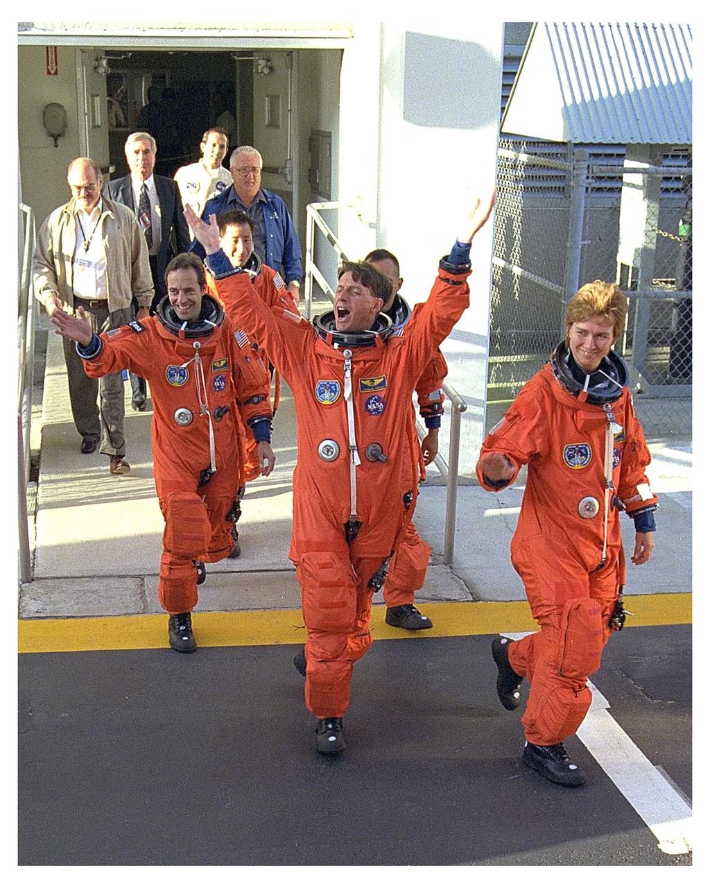 STS-84 Mission Specialist C. Michael Foale, at center, exhibits great enthusiasm for the upcoming Space Shuttle mission to onlookers during the dress rehearsal of the crew’s walkout from the Operations and Checkout Building. He and the other six STS-84 crew members are participating in an abbreviated practice countdown to launch called the Terminal Countdown Demonstration Test (TCDT). In front of Foale is Mission Specialist Elena V. Kondakova, a Russian cosmonaut. Behind Foale, from left, are Mission Specialist Jean-Francois Clervoy, an astronaut with the European Space Agency; and U.S. astronauts and STS-84 Mission Specialists Edward Tsang Lu and Carlos I. Noriega. Already out of camera view are Pilot Eileen Marie Collins and Commander Charles J. Precourt. During the sixth ShuttleMir docking, Foale will take his place aboard the Russian Space Station Mir as a member of the Mir 23 crew, replacing U.S. astronaut Jerry M. Linenger, who will return to Earth on Atlantis. Launch of STS-84 is targeted for May 15